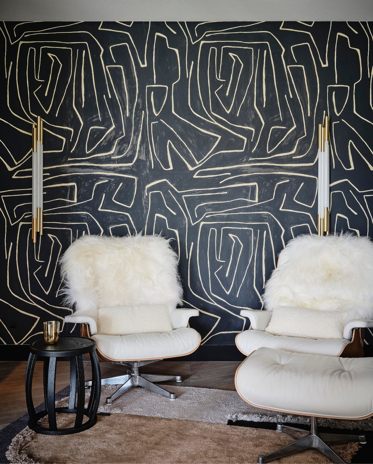Linda: ‘De Eames lounge chairs namen de eigenaars mee uit hun andere woning. Ik gaf ze meer karakter met de schapenvellen.’ Grafitto behang Kelly Wearstler, bijzettafel Maxalto, stalen bureaustoel Overgaard &amp; Dyrman. stijlvol wonen 08-2024 | Fotografie Space Content Studio