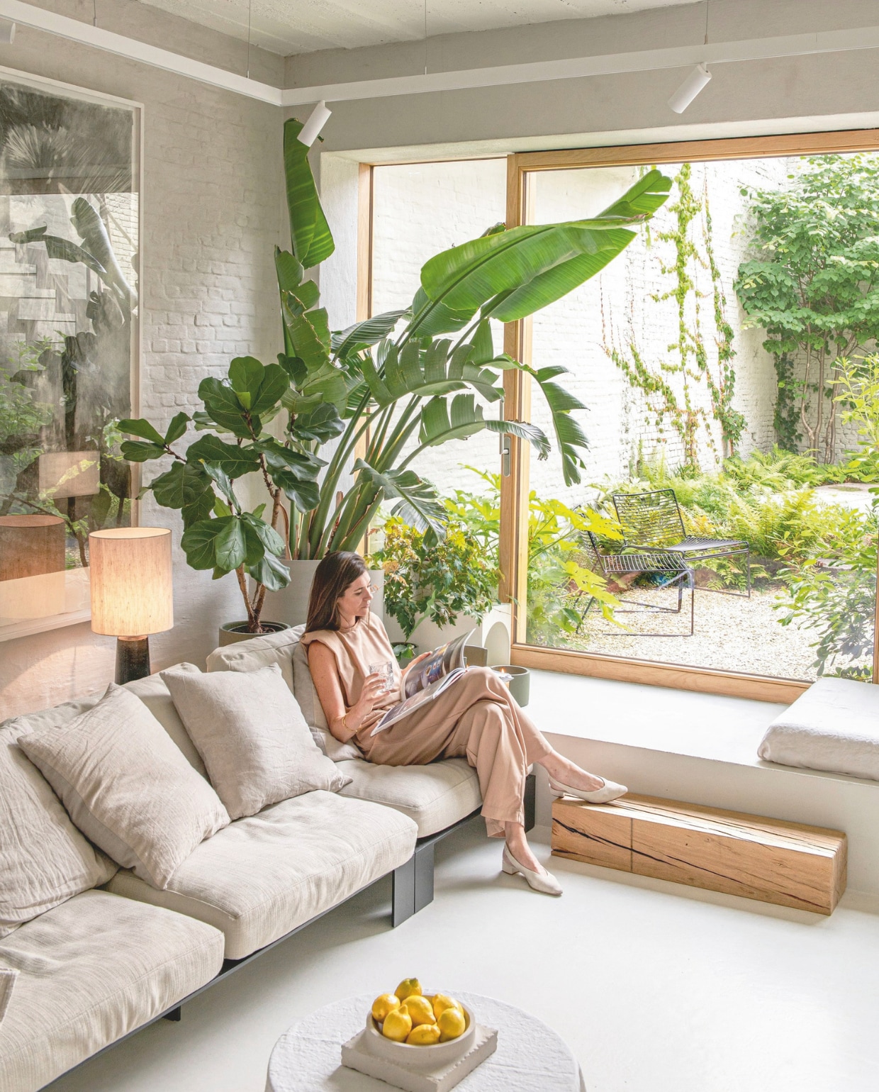 Bank Modular Lounge Sofa van Bea Mombaers, plafondspots Orbit, vintage lamp via Christiaensen & Christiaensen, kunstwerk Peter Morrens, oud rond tafeltje met linnen doek eroverheen, fruitschaal Kristina Dam, op de muur naturel kalei, vloerverf in de kleur William Off White van By Anouk.