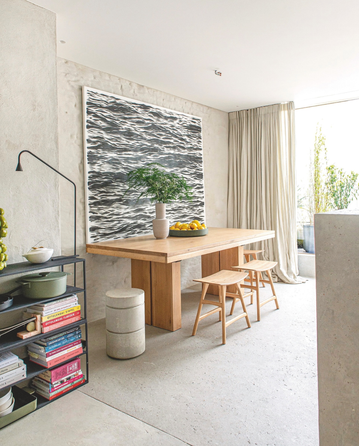 Boekenrek House Doctor, schalen uit zelf ontworpen collectie KOS voor D&amp;M Deco, tafellamp Trizo, bijzettafel annex kruk Concrete Stool van Serax, kunstwerk Fake Rinus van Louis Ingelaere, tafel Double en houten krukken Osso van Ethnicraft, linnen gordijnen By Anouk. De muurafwerking is naturel kalei, afwerking vloer Wabi (zelf ontwikkeld product. vtwonen 13-2024 | styling Jeske Weel | fotografie Caroline Coehorst