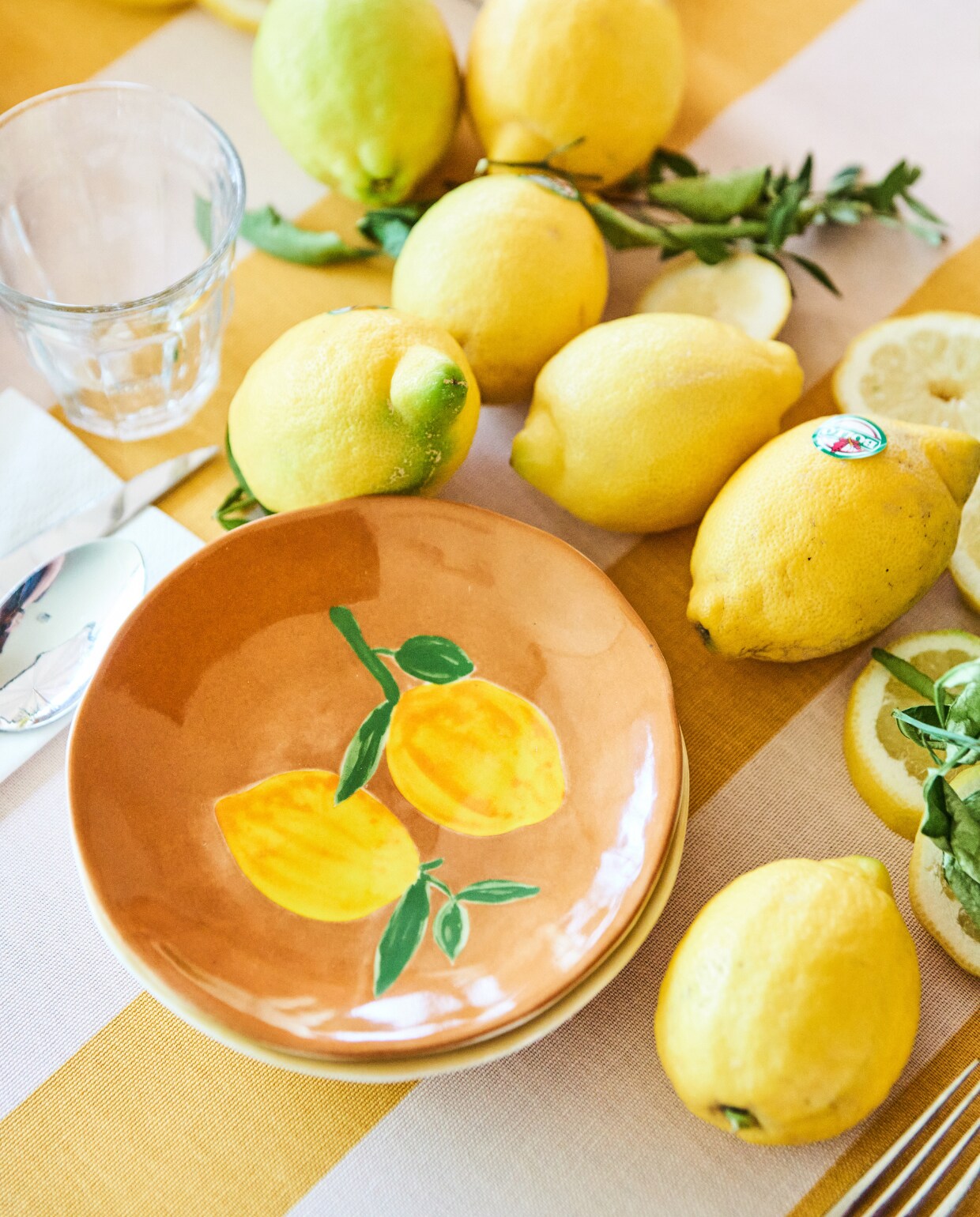 Bord Lemon van &amp;Klevering, 16 cm (Ø), set van 4 € 42,50 (debijenkorf.nl). Tafelkleed met streepdessin van Sylke gordijnstof, 150 cm breed, per strekkende meter € 6,- (kwantum.nl). Glazen, karaffen en bestek, privébezit restaurant dudok.nl. vtwonen 07-2023 | styling Marit Saladini | fotografie Bart Brussee