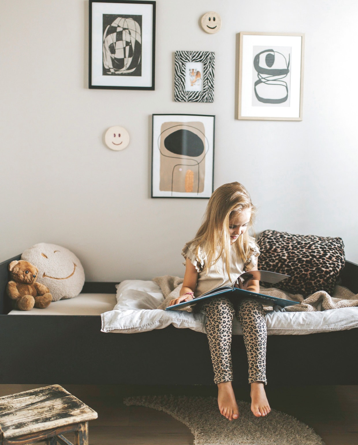 Vesper op haar bed met rond kussen van Atelier Pomme en luipaardkussen zelfgemaakt met stof van de markt. Vloerkleed Studio Jules. Smileys Marlot Ceramics via Etsy. Kaders en prints Wet Paint Boutique, Loods 5 en Wewonderwall. De houten kruk is van toen Bart Jan zelf kind was. vtwonen binnenkijkspecial 11-2024 | fotografie Merel Visscher
