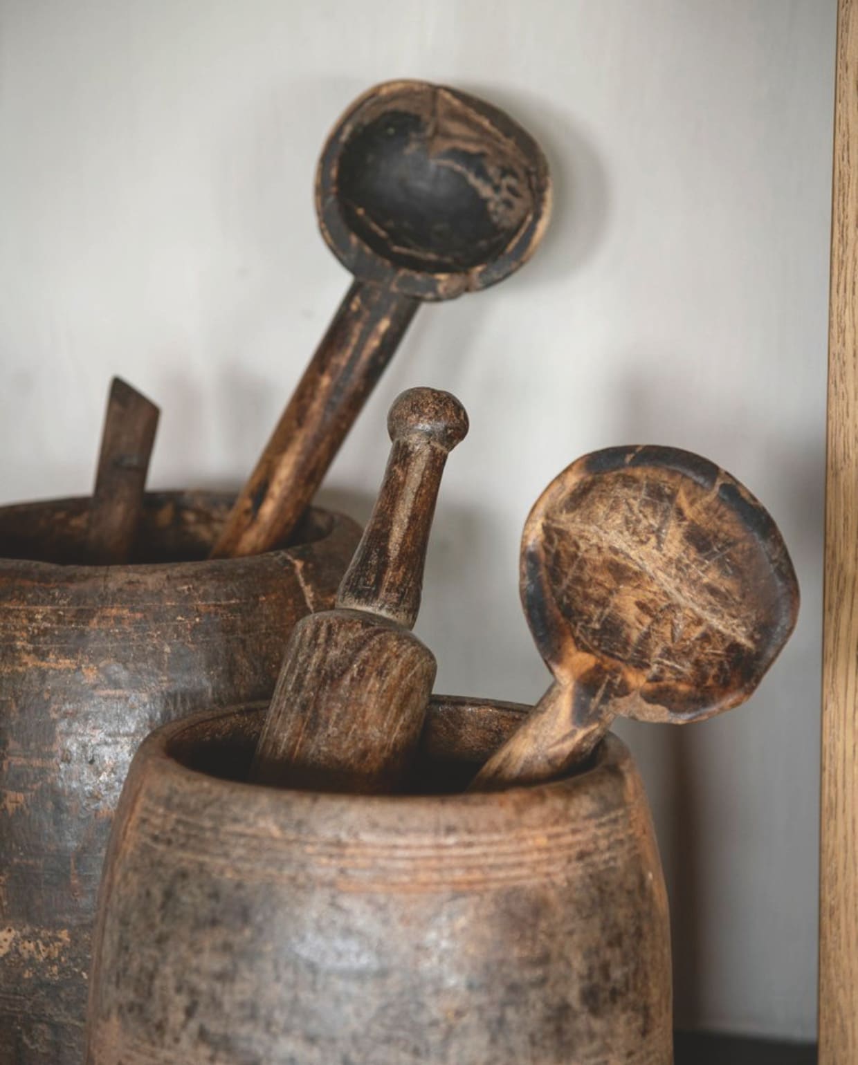 Op de houten planken in de keuken staan vintage Nepalese kruidenpotten, gevuld met keukenaccessoires uit een ver verleden. vtwonen landelijk 08-2024 | fotografie Jonah Samyn