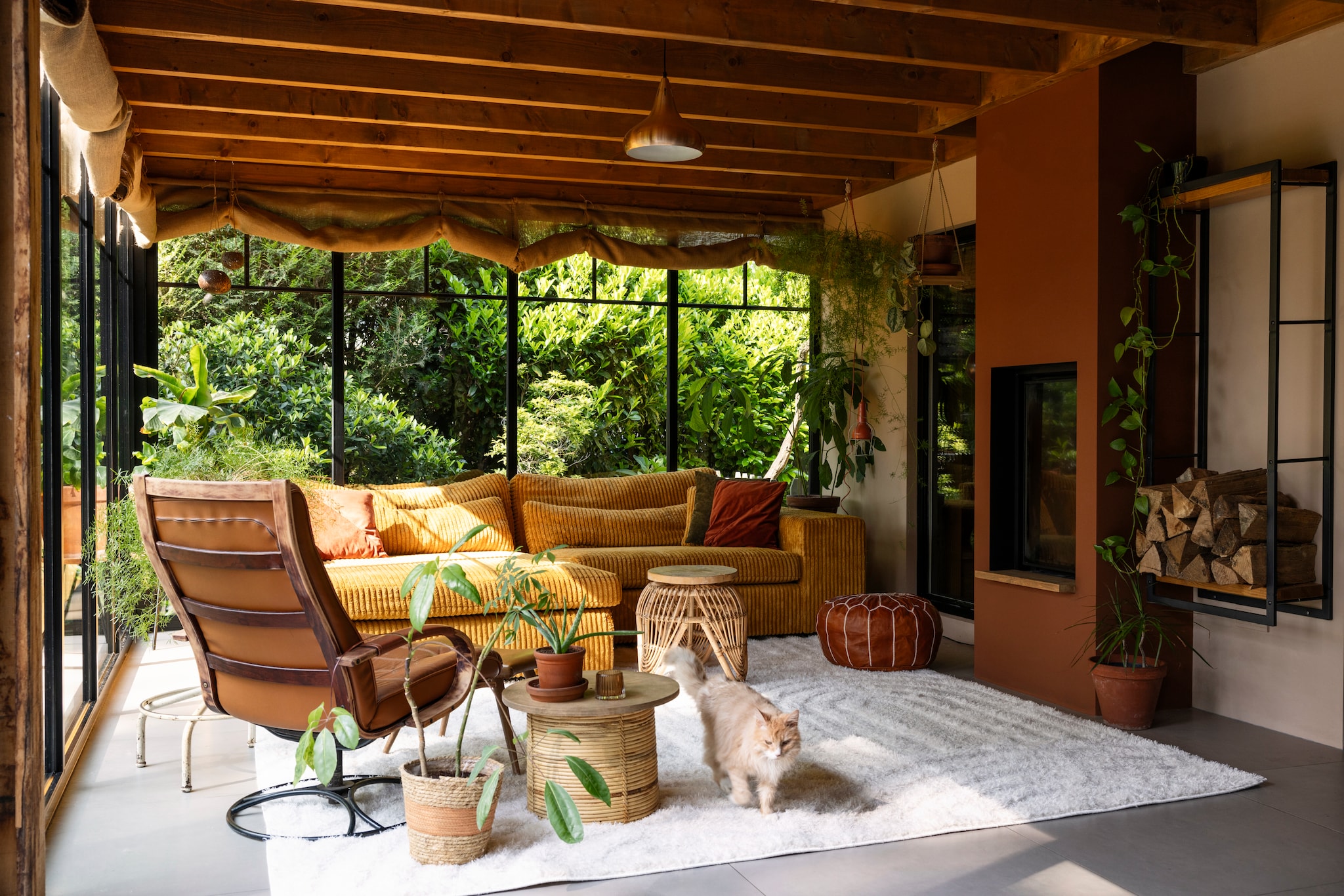 Wandkleur Transcend van Histor, wandkleur schouw Histor ppg16-23 Tampico Brown. Vloerkleed Lova Arches Creme van Volero, vintage draaifauteuil gekregen van een vriendin, rieten bloempot Action, voorste tafeltje omgekeerde plantenbak van Bloomingville met zelfgemaakt houten blad, achterste rotan tafeltje Big Bazar met zelfgemaakt houten blad van oud steigerhout. Marokkaanse poef The Souks, bank Hulk van PureWonen, verticale haard Bodart &amp; Gonay Concept Green 540 Dfv. vtwonen 02-2025 | styling Ilona Jongepier | fotografie Dana van Leeuwen