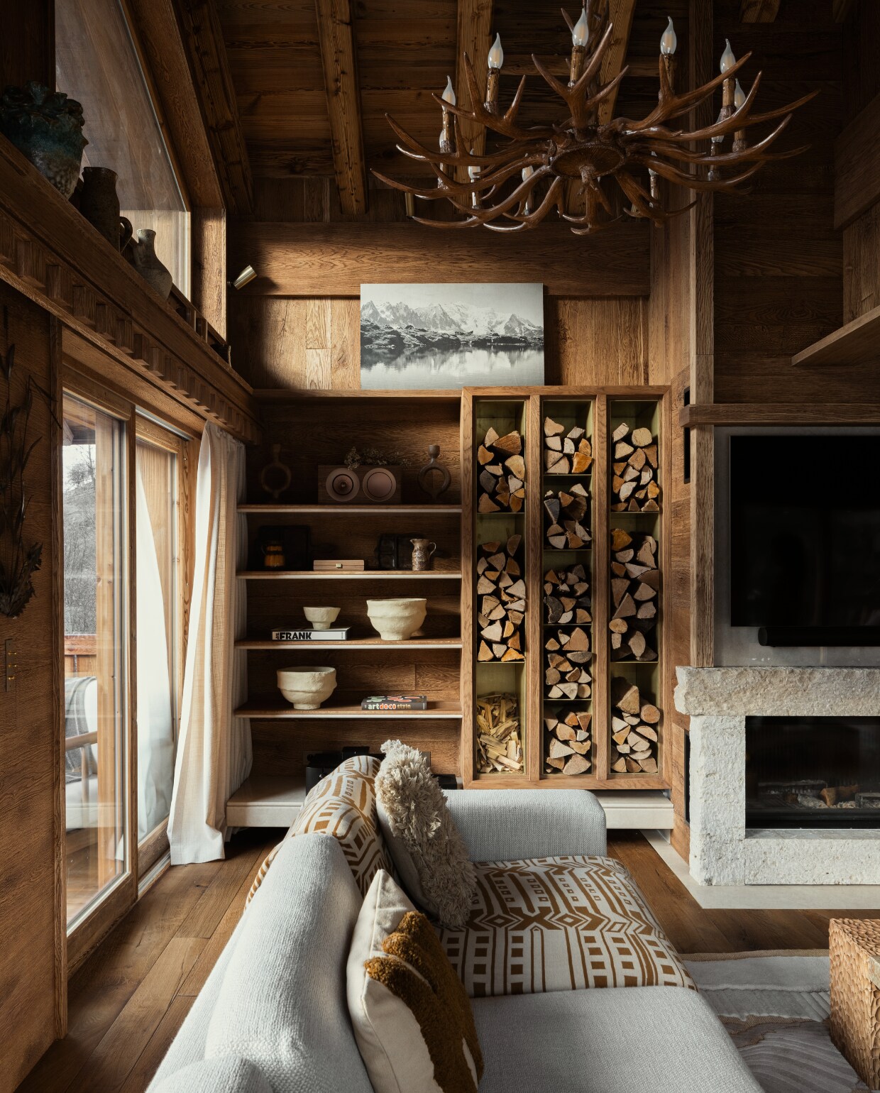 Het haardhout is opgeborgen in een kast van messing en hout. Bank van Bolia stijlvol wonen 08-2024 | Productie Living Inside | Fotografie Ramona Balaban