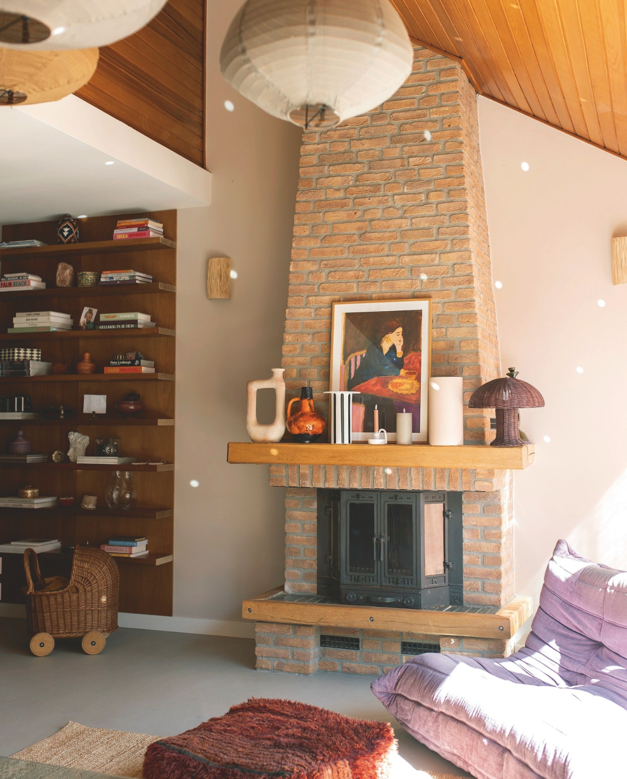 Muurkleur Calm van Pure &amp; Original. Vloer Betonlooks. Boekenkast zat al in het huis. Hanglampen en rotan lamp HK Living. Wandlampen zelfgemaakt. Schilderij Tiny Stories. Vazen Household Hardware, vintage, HK Living en Bloomon. Paarse stoel Togo van Ligne Roset. Poef Merel in Wonderland. Kinderwagen erfstuk. vtwonen binnenkijkspecial 11-2024 | fotografie Merel Visscher, Beate vieth