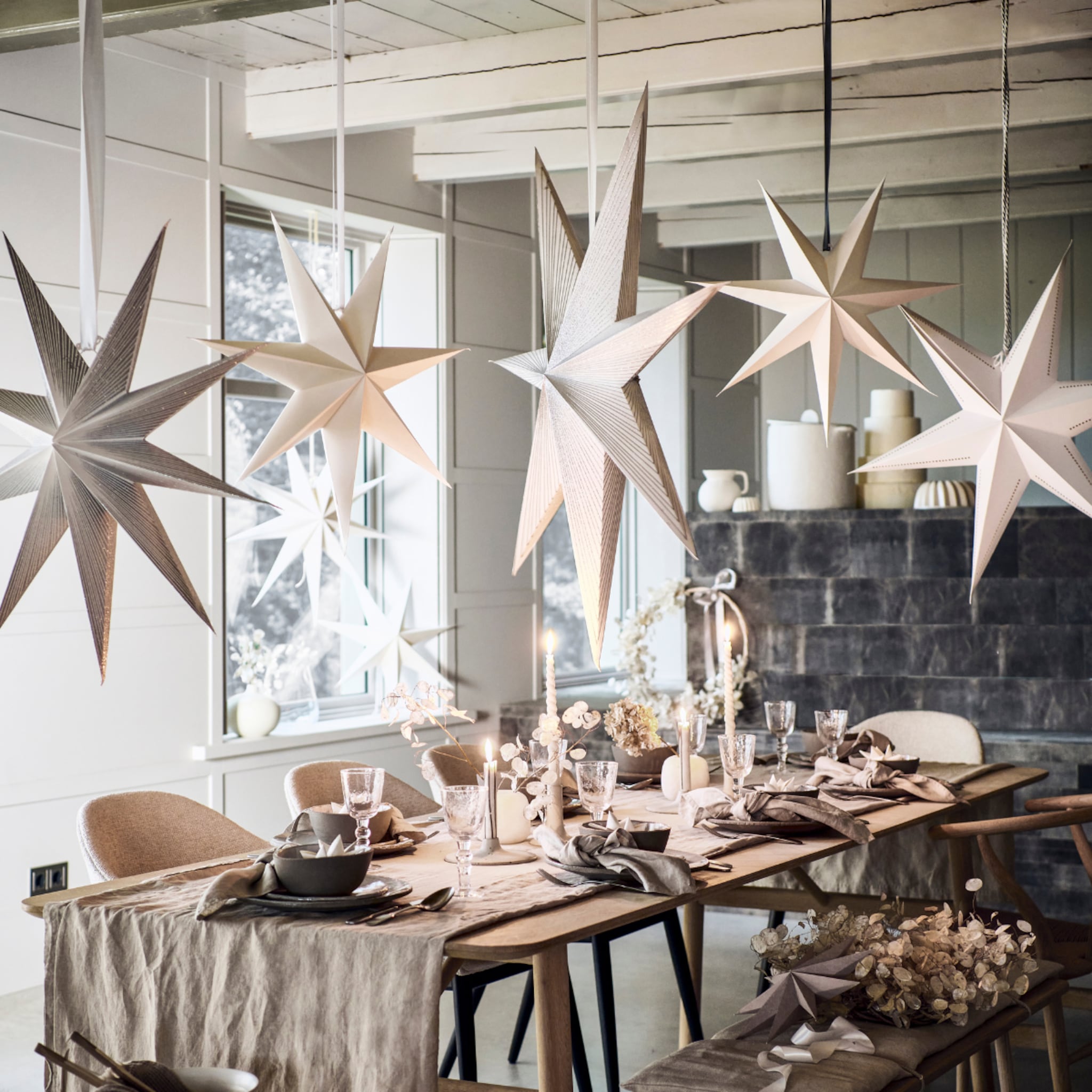 Kersttafel met feestelijk servies, een tafelloper, kaarsen en hangende sterren van papier