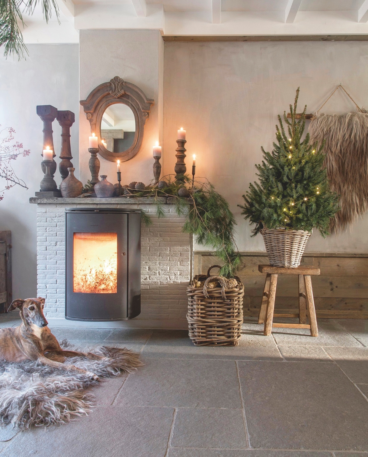 Kandelaars, balusters, antieke halskruiken, schapenvacht, oude houten kruk, schapenvacht wandkleed en ossenoog De Buitenkans. vtwonen landelijk 08-2024 | styling Peet! Styling | fotografie Joyce Vloet