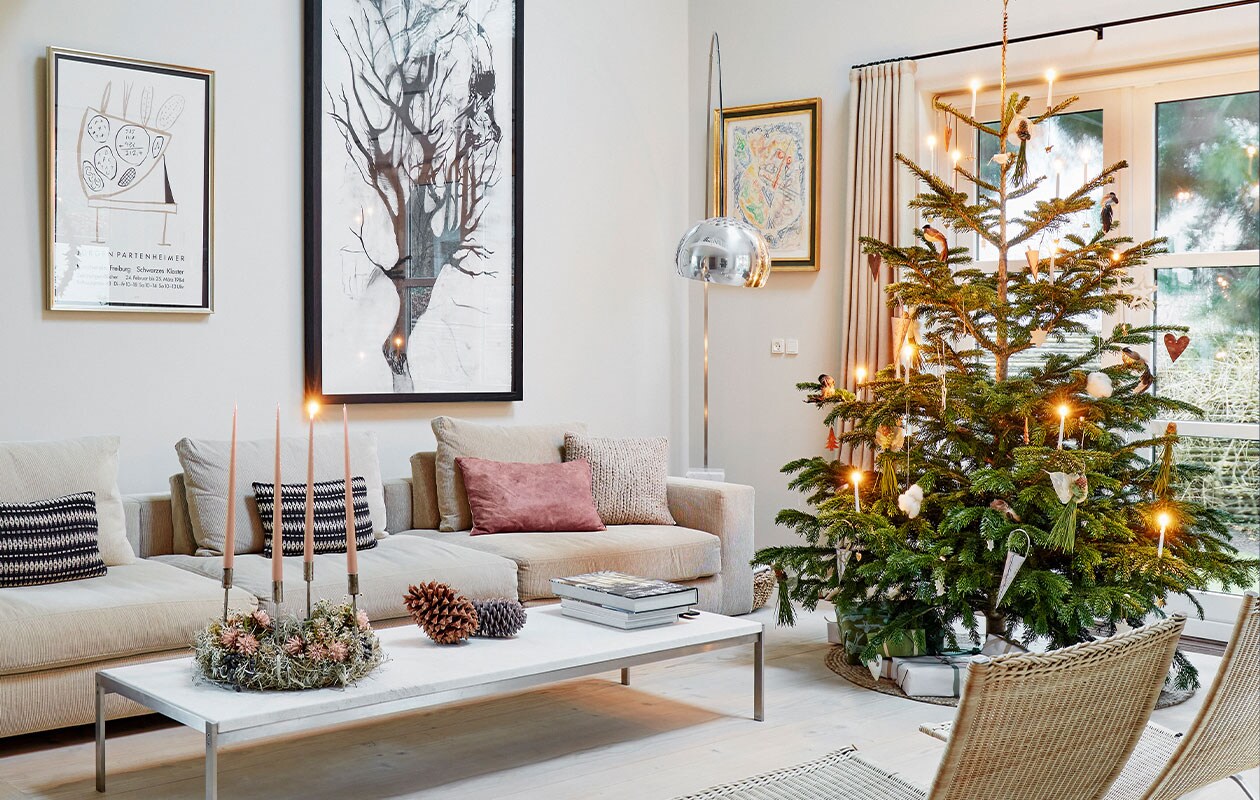 Bank Baseline van Eilersen, kussens Tapet-Cafe. Marmeren koffietafel Poul Kjærholm, kerstkrans met kaarsen gemaakt door Malou Karberg en Henrietta. Inkttekening boven bank Cathrine Raben Davidsen, kunstwerk links naast raam Egill Jacobsen. Lamp Arco van Achille &amp; Castiglioni voor Flos. vtwonen 12-2021 | Productie Living Inside | Fotografie Martin Slyst