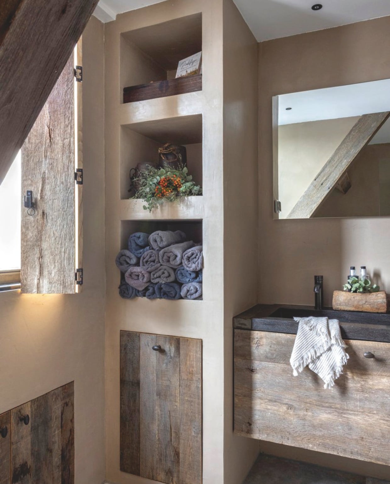 Op de muur in de badkamer: beton ciré in de kleur Avellana van Beton Ciré Nederland. Op de vloer Cera Stones van Steenbergen Tegels. Marianne ontwierp zelf de vakkenkast en het zwevende badmeubel, een timmerman maakte het op maat van massief eikenhout geleverd door Crumwood. vtwonen landelijk 08-2024 | fotografie Anneke Gambon