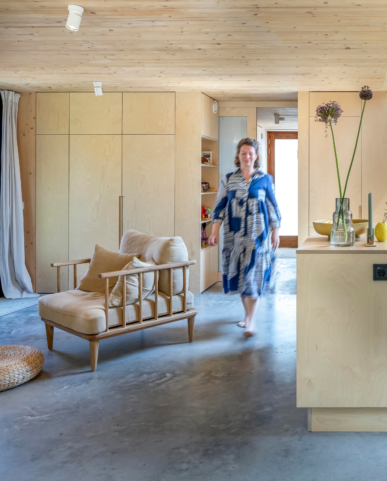 Een matglazen schuifdeur scheidt de entree van de woonruimte. Fauteuil en schaal Loods 5. Poef Ikea, geel vaasje Des Pots, kandelaar Floris Hovers. vtwonen 01-2025 | fotografie Hennie van Belkom