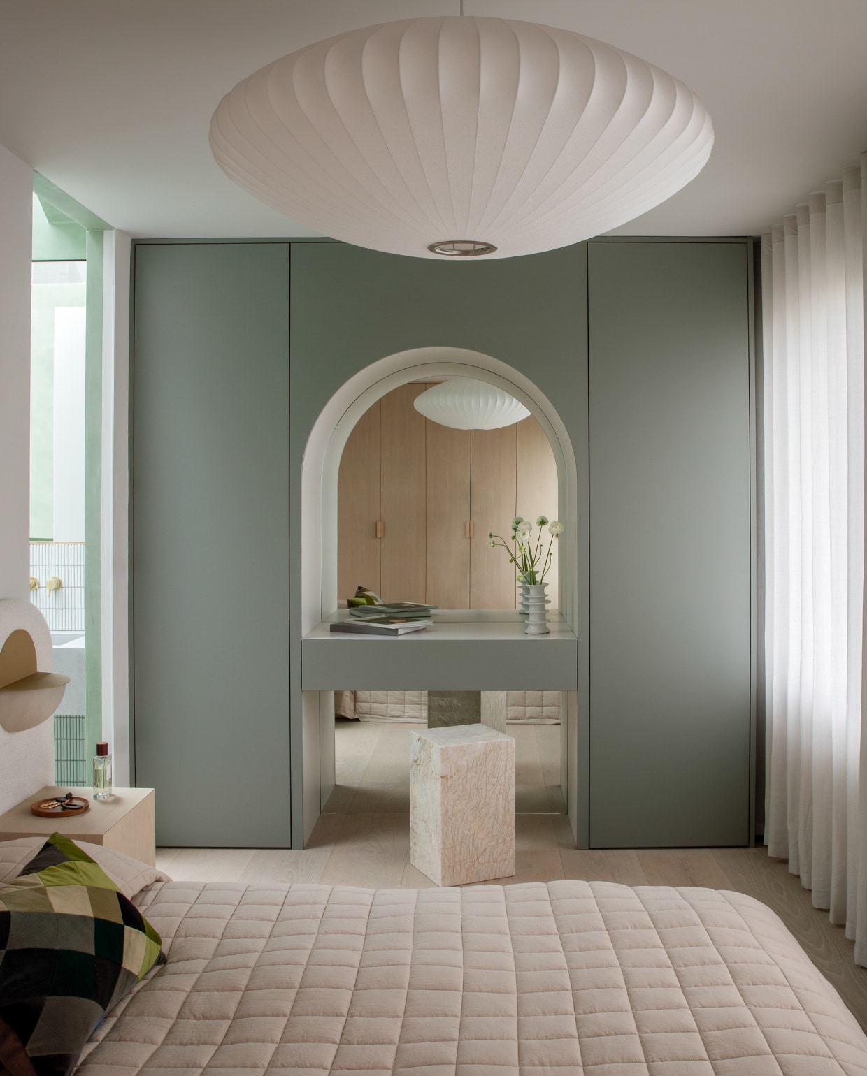 Het bedframe is op maat gemaakt en gestoffeerd door The Ripple Furniture Co. Wandlampen Luno van Simone &amp; Marcel, hanglamp Nelson Saucer Bubble van Hay. Dankzij de spiegel in de poortvormige nis van de toilettafel lijkt de ruimte door te lopen. stijlvol wonen 01-2025 | productie Living Inside | fotografie Ruth Maria Murphy