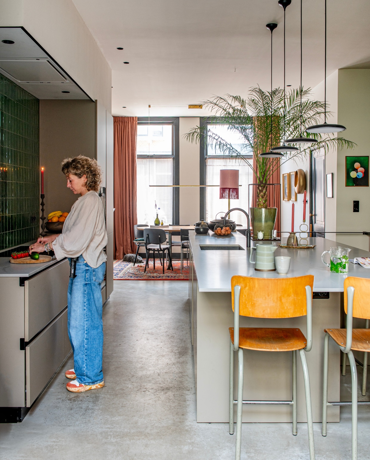 Keuken, wandtegels Kol van Intercodam. Kraan Quooker. Krukken, kandelaars kringloopwinkel, hanglampen Flos, theepot Broste Copenhagen, mok Lilo Ceramics Studio, karaf Iittala, kunstwerk rechts Derrick Ofosu Boateng, schemerlamp Madame Garage, stoelen Revolt van Friso Kramer heruitgebracht door Hay, vloer beton. Verfkleur plafond Skimming Stone, muur rechts Card Room Green en kozijnen Off-Black van Farrow & Ball.    vtwonen 01-2025 | productie de binnenkijkers | fotografie caroline coehorst