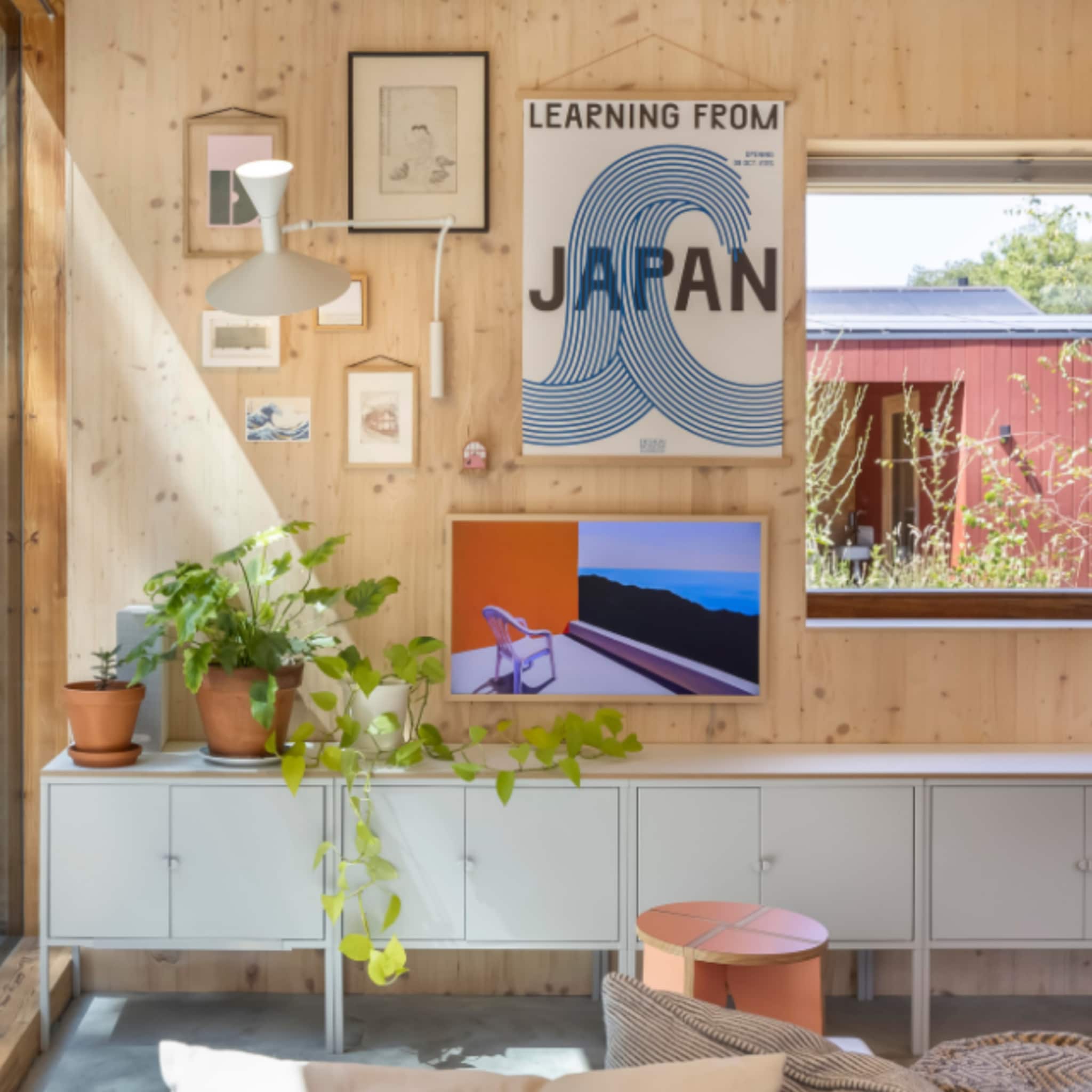 Gallery wall van kunstwerken, posters en lampen om een televisie