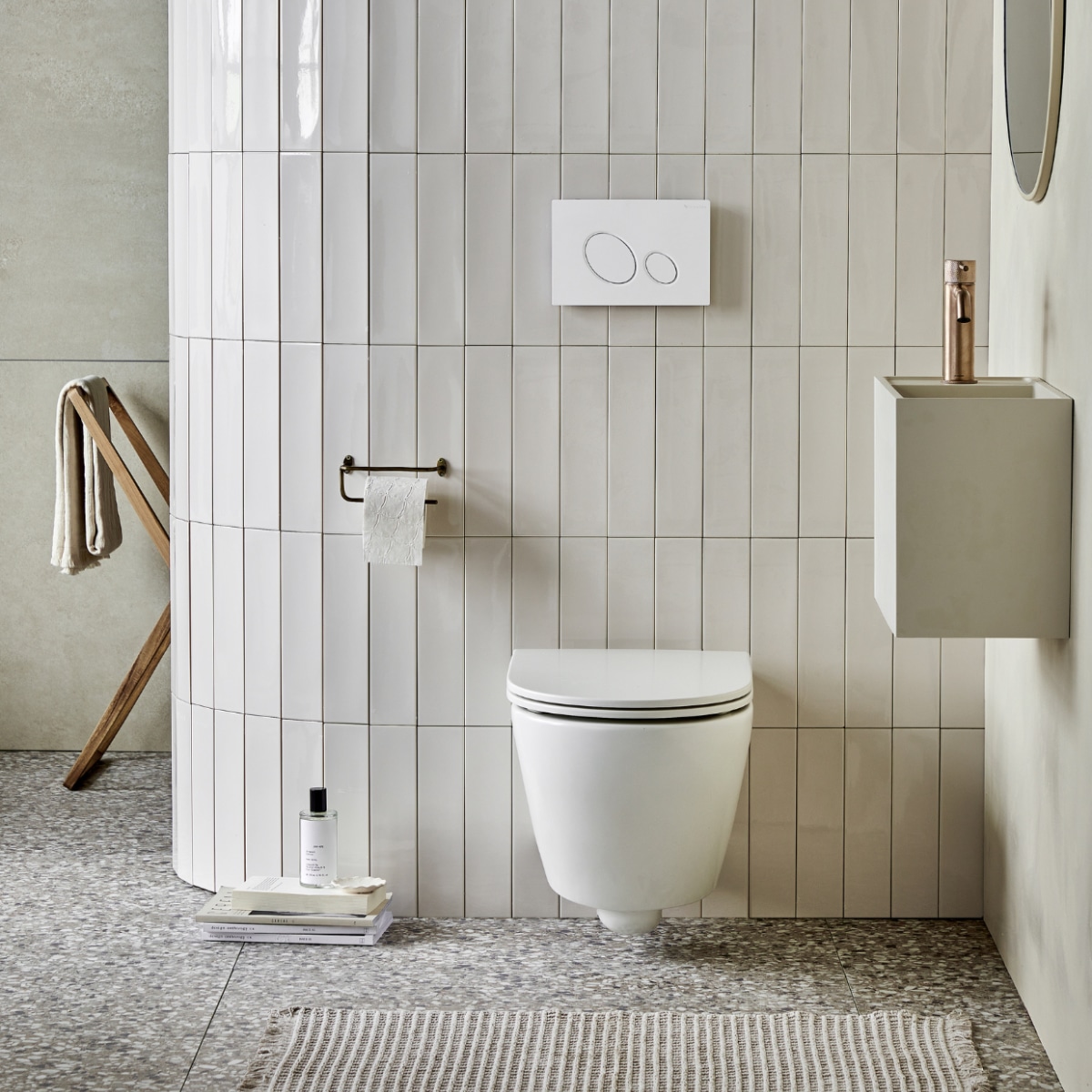 Keramieken toilet Bloc in Mat Wit, met soft close-zitting , ook in matzwart en matzand. Top solid toiletwas-tafel Wide in zand, 40x30x22 cm (bxdxh)ook in grijs, wit en zand en in materialen marmer wit, bruin, zwart en zilvergrijs. Op de vloer: vloer- en wandtegel Terrazzo Clay Flakes, 90x90 cm. Op de afgeronde muur: wandtegel Shapes Vapor glans, 7,5x30 cm. Op de achterwand: vloer- en wandtegel Raw Sand Mat, 80x80 cm,. M.m.v plieger.nl (wastafelkraan Roma), vtwonen.nl/shop (hanglamp van Bloomingville), zarahome.com (roomspray, houten wasrek, handdoek, messing toiletrolhouder, ronde spiegel), hm.com (badmat). Overig privébezit. vtwonen 05-2023 | productie Tanja Saarberg | styling Sanne Ketelaar | fotografie Peggy Janssen