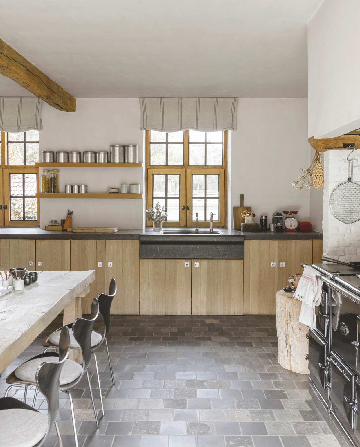 Keuken van eikenhout en Belgisch hardsteen naar ontwerp van Dorien. De originele tegelvloer werd hersteld. Fornuis Aga. vtwonen landelijk 01-2025 | styling Marc Heldens | fotografie Verne Photography