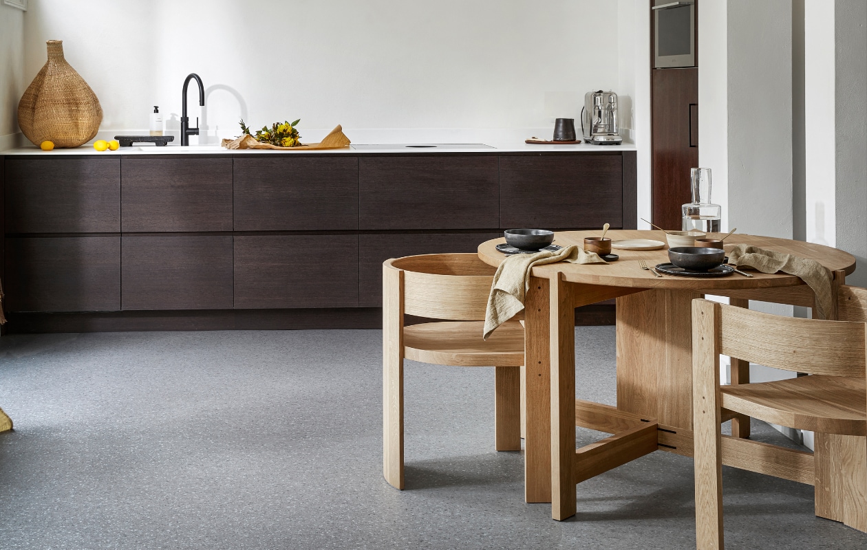 vtwonen collectie Novilon vloer in Graniet, per m² € 36,75 (excl. installatie). M.m.v. letoile.store (eikenhouten eettafel en stoelen van Kristina Dam, linnen servetten, mokken met schotels van Serax, keramieken servies), justanothershop.nl (knoflookvormige mand, snijplank, zwarte kan), lidor.nl (gordijn van Numero 74). Overig privébezit. vtwonen 07-2023 | productie Tanja Saarberg | styling Marlies Does | fotografie Peggy Janssen