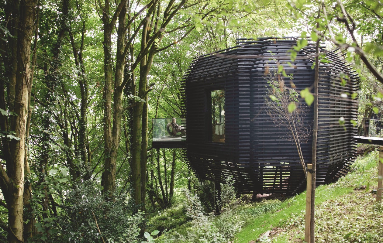 Elke Woodland Suite is een hexagonaal gebouw op stelten, waardoor het bouwwerk op het groen lijkt te drijven. Stijlvol Wonen 01-2025 | productie Living Inside | fotografie Ruth Maria Murphy