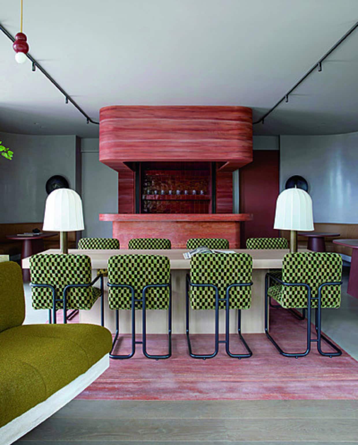 De Clubhouse voor de gasten van de Woodland Suites met centraal een eiken tafel. Op de achtergrond op maat gemaakte leren banken en roodbruine tafels. Kunstwerk van Manolo Ballesteros. Voor het raam staat de Knitting Lounge Chair van Audo Copenhagen. Stijlvol Wonen 01-2025 | productie Living Inside | fotografie Ruth Maria Murphy