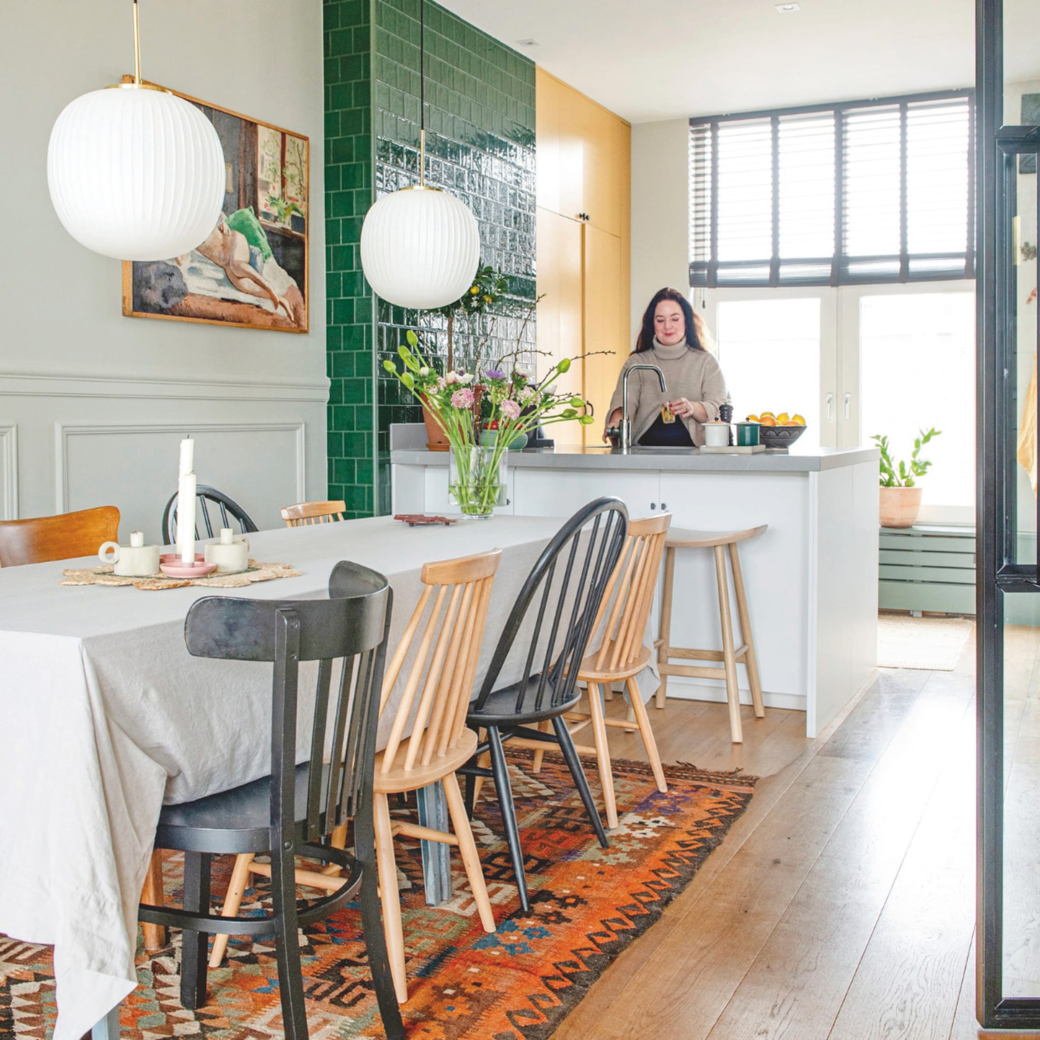 Scandinavische eetkamer met een groen betegelde wand in de keuken