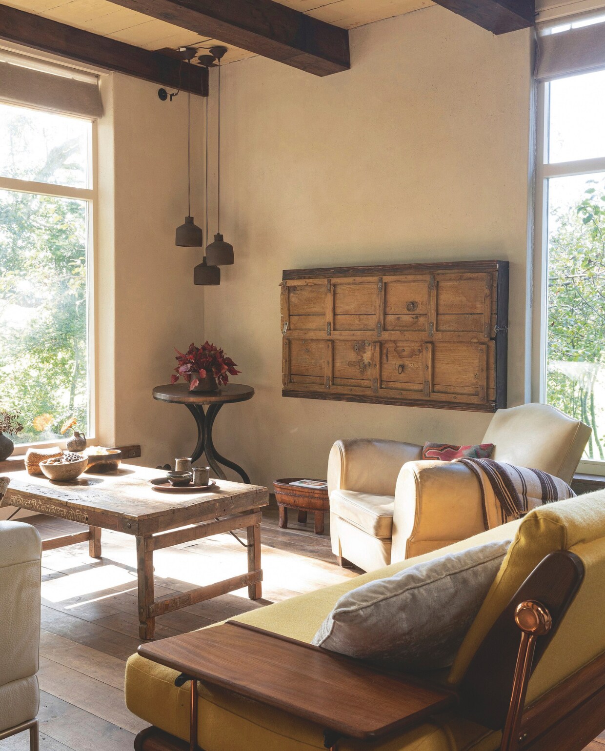 Vintage meubels, organische materialen en zachte kleuren bepalen de woonkamer. Soortgelijke salontafel bij Aura Peeperkorn, soortgelijke hanglampen bij Hoffz. vtwonen landelijk 01-2025 | productie Taverne Agency | styling en fotografie Tessa Jol