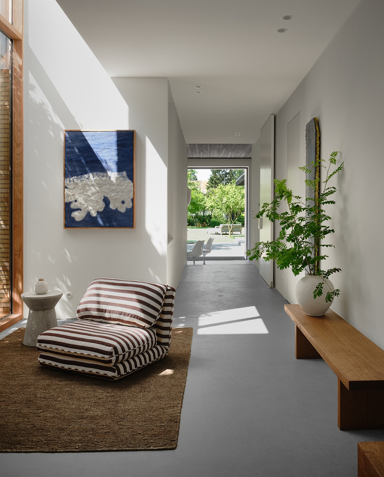 De grote houten raampartij geeft de hal extra warmte. Fauteuil Zara Home, tapijt Loook. stijlvol wonen | 2-2025 | fotografie Mr Frank | tekst Maya Toebat