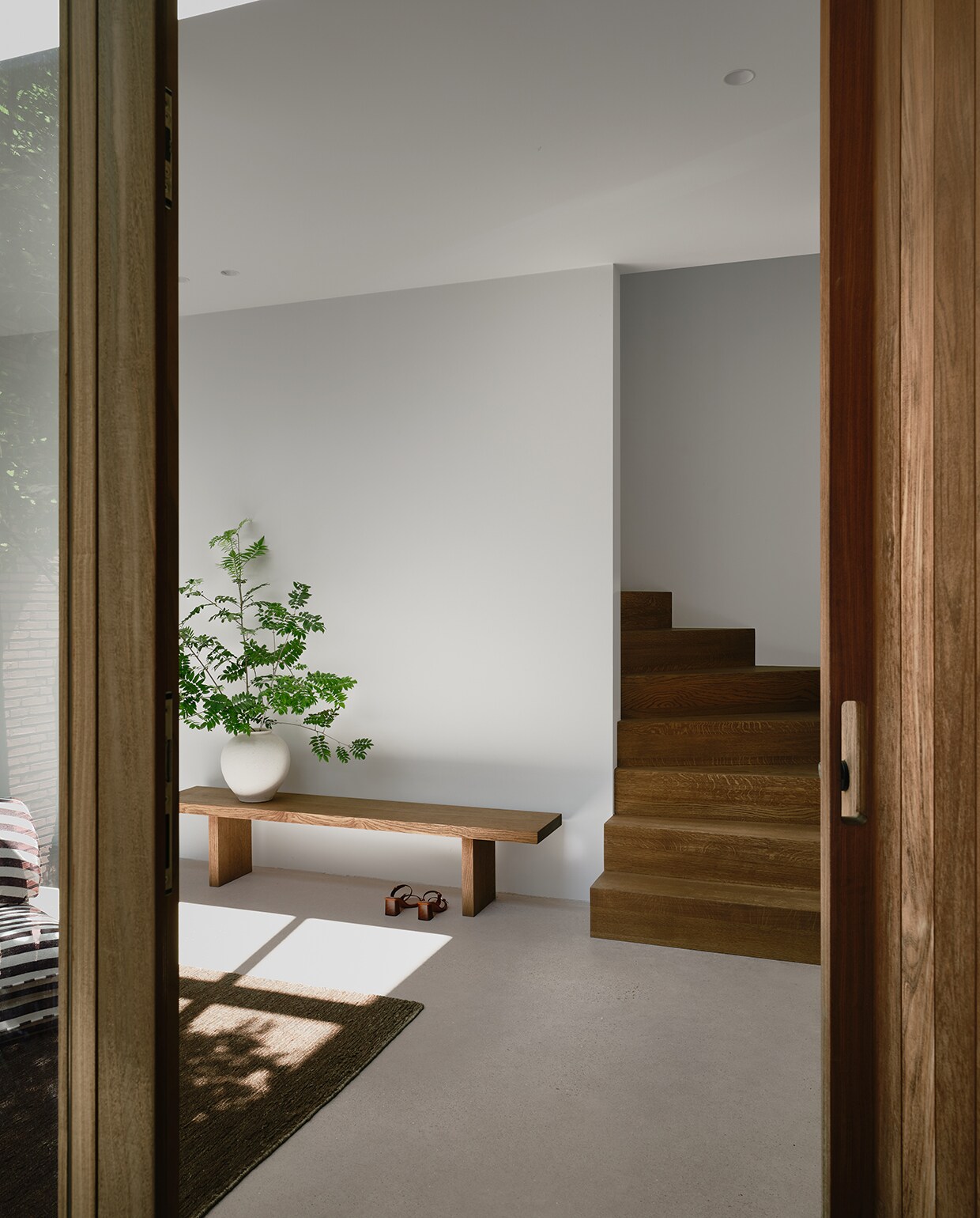 In de hal valt de inspiratie uit minimalistische Japanse woningen op. De eiken bank is op maat gemaakt door de trappenbouwer. stijlvol wonen 2-2025 | fotografie Mr Frank | tekst Maya Toebat