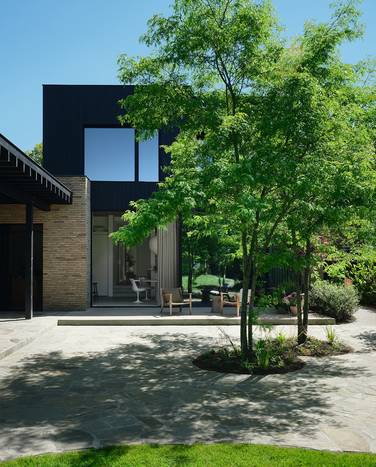 De gevel combineert zwart gebeitst thermowood met gele steen Linea 1017  van Vande Moortel. Het terras, met stapstenen en twee valse christusdoorns, biedt zowel zon als schaduw. stijlvol wonen 2-2025 | fotografie Mr Frank | tekst Maya Toebat