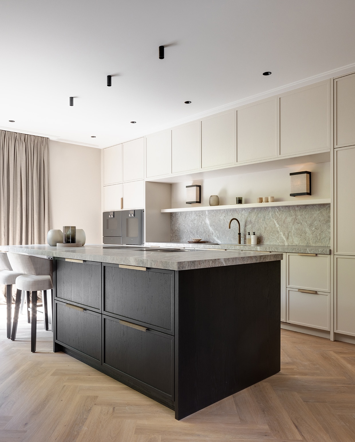 De open eetkeuken in de aanbouw is een ontwerp van Céline van Haaren Interiors en werd gerealiseerd door haar eigen meubelmaker. Het eiland is zwart gebeitst, de verfkleur op alle andere kasten is Rolling Fog van Little Greene. Wandlamp Piotello uit de collectie van Maretti Lighting, plafondspots Modular, eiken vloer Palmparket. stijlvol wonen 2-2025 | Fotografie Jurrit van der Waal | Tekst Yvonne van Galen