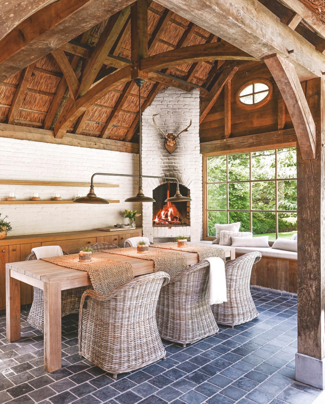 Eettafel en stoelen Prananatha. Soort-gelijke tafellopers Nordic Nest. Lamp Tierlantijn. Buitenkeuken gebouwd door Axel Ketele, Timberframing. Vloertegels blauwe hardsteen. vtwonen Landelijk 2-2025 | Fotografie Claude Smekens | Tekst Yvonne van Galen