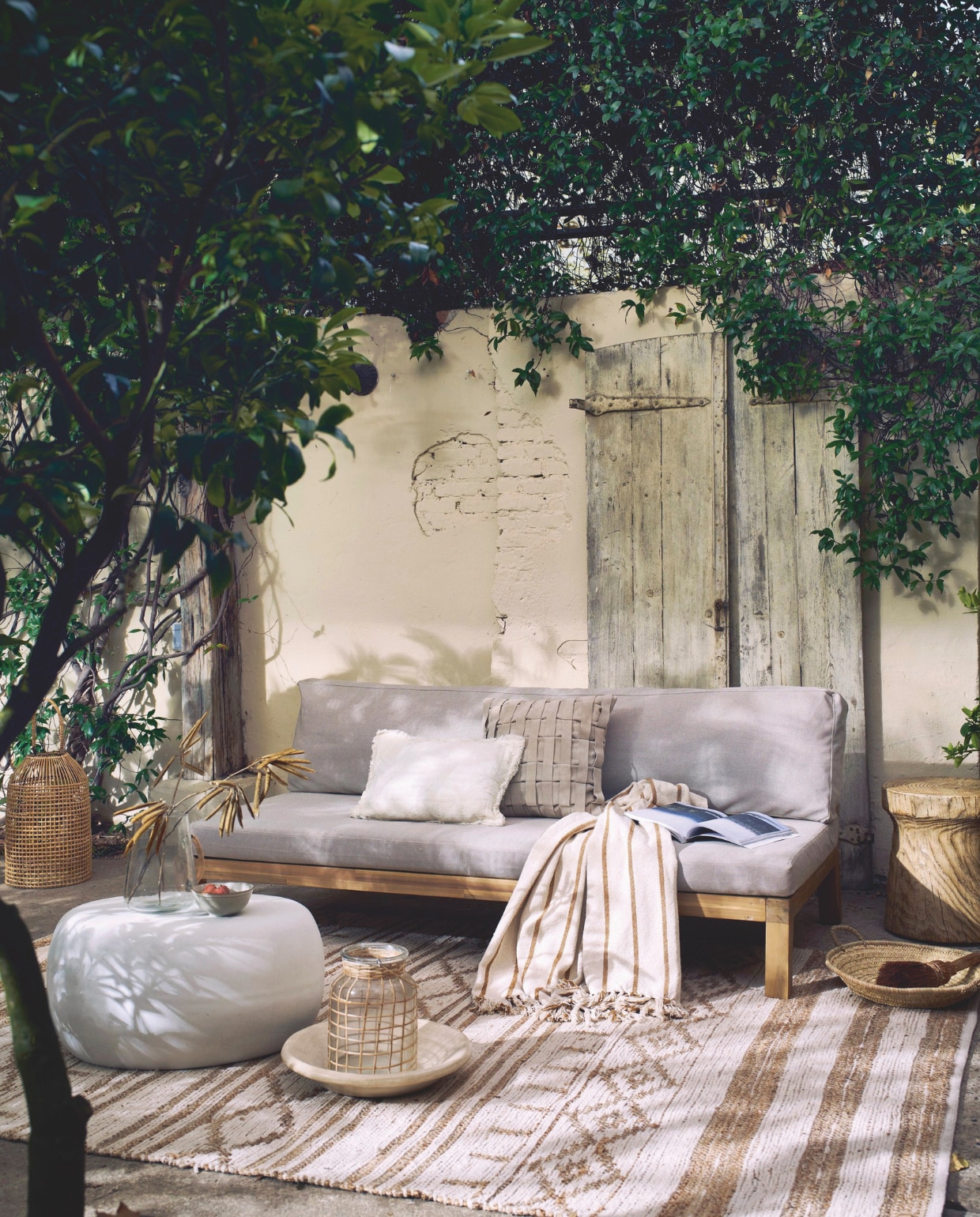 Acaciahouten 3-zits tuinbank Relax in naturel/zand, 180x70x90 cm (bxdxh) € 749,- en fiberclay bijzettafel Pebble in betonlook wit, diverse maten vanaf 50x50x35 cm (lxbxh) € 179,- M.m.v. madamstoltz.nl (vloerkleed, mand, plaid, wit kussen, vaas met rieten handvat), iblaursen.nl (lampion), vtwonen collectie via shop.vtwonen.nl (glazen en gevlochten kussen), nordal.com (windlicht), basiclabel.nl (houten bijzettafel Woood), householdhardware.nl (tadelakt schaal). Overig privébezit. vtwonen 03-2025 | styling cleo scheulderman | fotografie jeroen van der spek