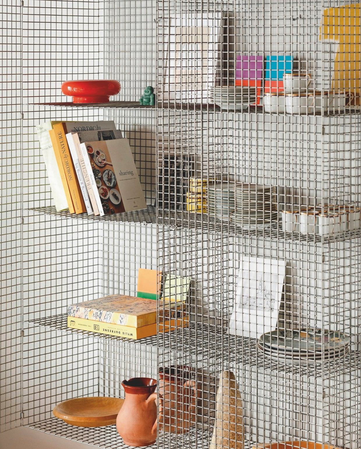 De open Wire C-kast van Muller Van Severen, gevuld met souvenirs, is een echte eyecatcher. Stijlvol Wonen 03-2025 | Fotografie Stie De Neve | Tekst Maya Toebat