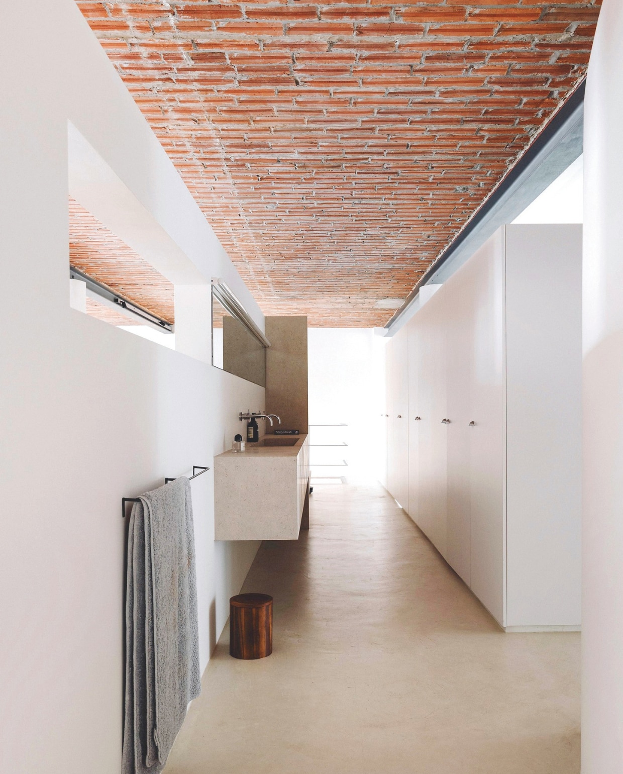 De badkamer met ruime wastafel is verbonden met de keuken via een open muur op ooghoogte. Het handdoekrek is van het Belgische merk Illus. Stijlvol Wonen 03-2025 | Fotografie Stie De Neve | Tekst Maya Toebat