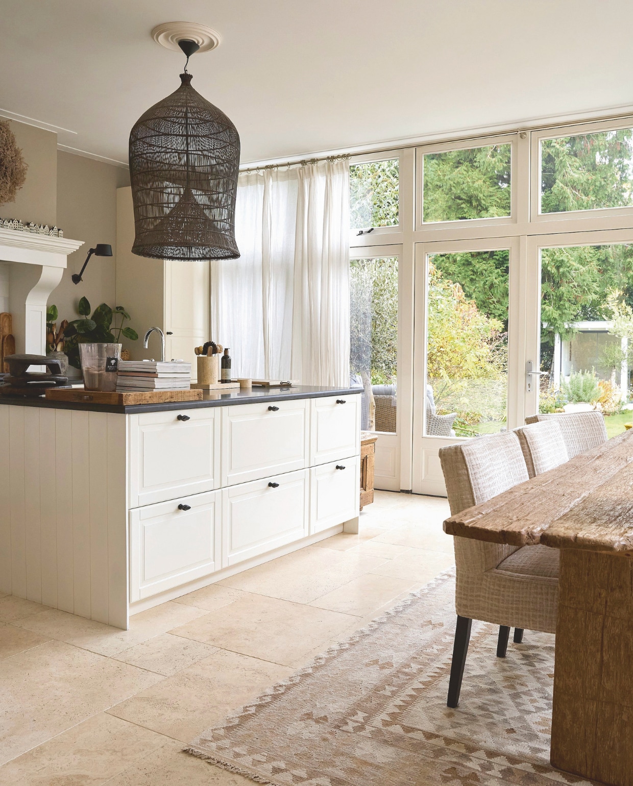 Keukenbasis Ikea (Metod fronten Bodbyn ecru) met fornuis van Lacanche via Kookwinkel Oldenhof, en een natuurstenen aanrechtblad en travertin vloer van Meisjes van Steen. Indonesische hanglamp van Couleur Locale. Muurverf Khaki van Painting the Past. vtwonen Landelijk 02-2025 | styling Marianne Luning | fotografie Tjitske van Leeuwen