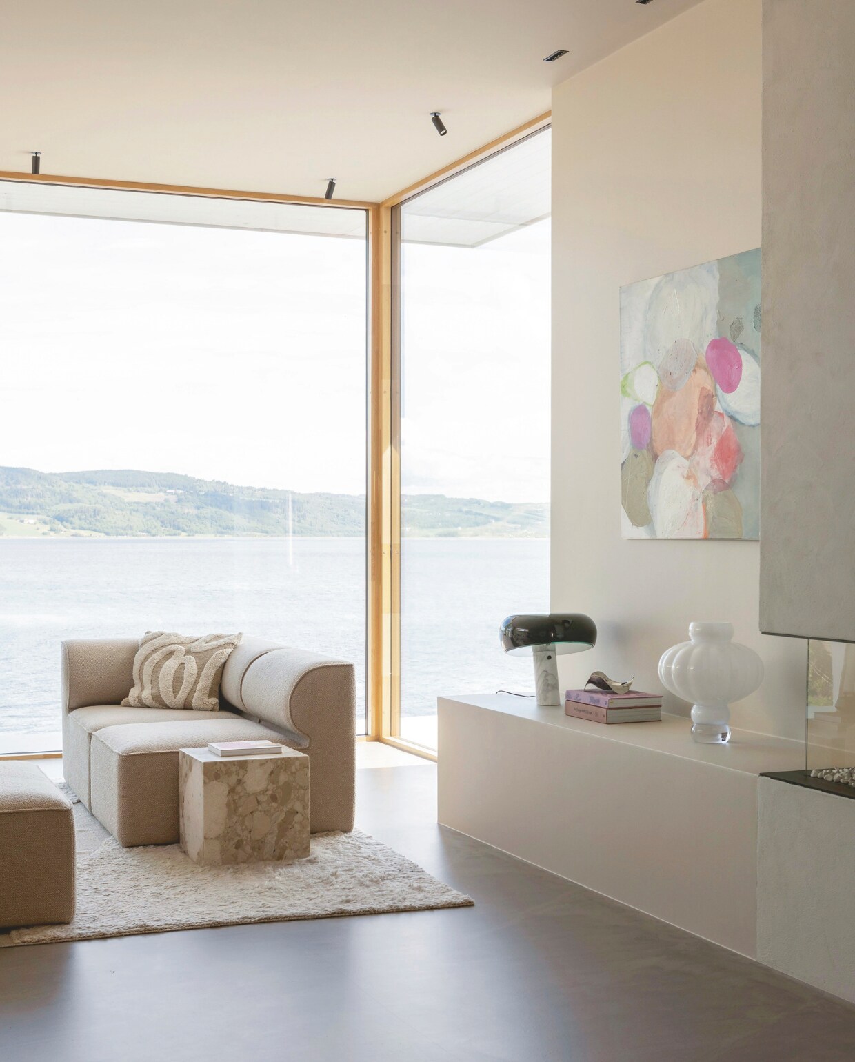 De Matrix haard van Faber zorgt voor sfeer op winterse avonden. Ernaast een kunstwerk van Kristine Hasseløy. Witte Balloon Vase van Louise Roe. Tafellamp Snoopy van Flos. Kussen H&amp;M Home. Stijlvol Wonen 03-2025 | Fotografie Anne Bråtveit | Tekst Caroline Westdijk