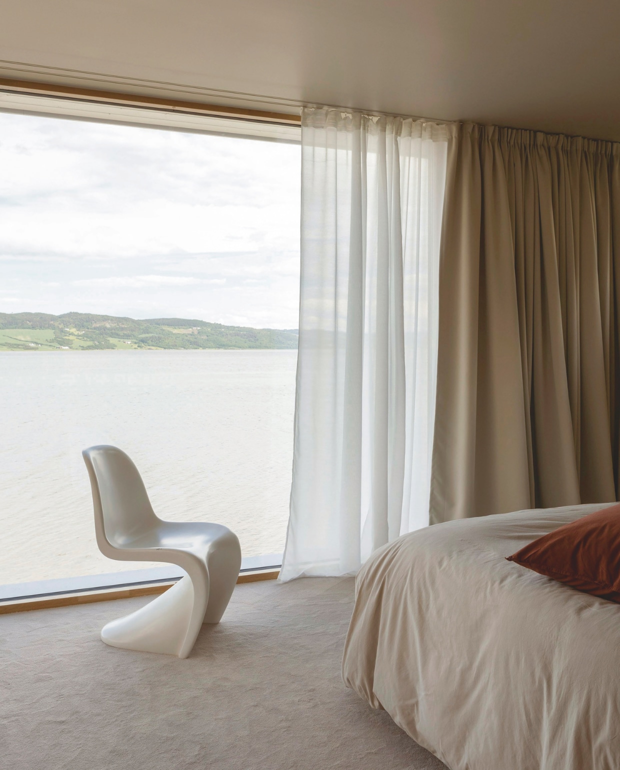 De slaapkamer heeft uitzicht op de fjord. Panton Chair van Vitra. Tapijt Fargerike. Gordijnen Ellos. Stijlvol Wonen 03-2025 | Fotografie Anne Bråtveit | Tekst Caroline Westdijk
