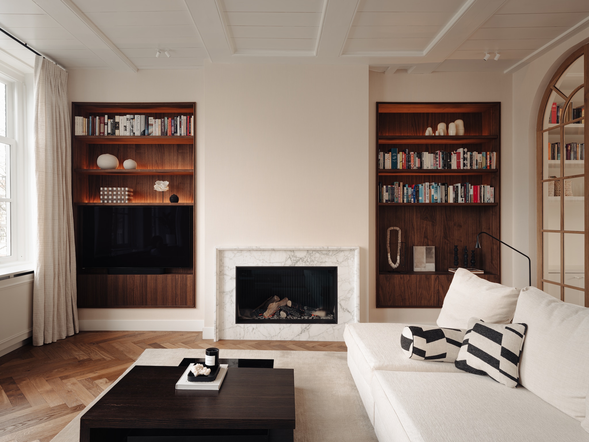 En-suiteverdeling op maat gemaakt door Tom van Gijzel Interieurs. Maatwerkkast Kluster Interieurbouw. Behang Greenland. Vloer gelegd door Palmparket. Bank Flexform. Kussens Nobilis. Salontafel met draaibaar middenblad uit vorige huis van de bewoners. Vloerkleed Massimo Copenhagen. Natuursteen voor de haardombouw House of Stone. Spots Wever & Ducré. vtwonen 06-2025 | styling Anniek de Pont en Sebastiaan van Maanen | fotografie Mart Goossens