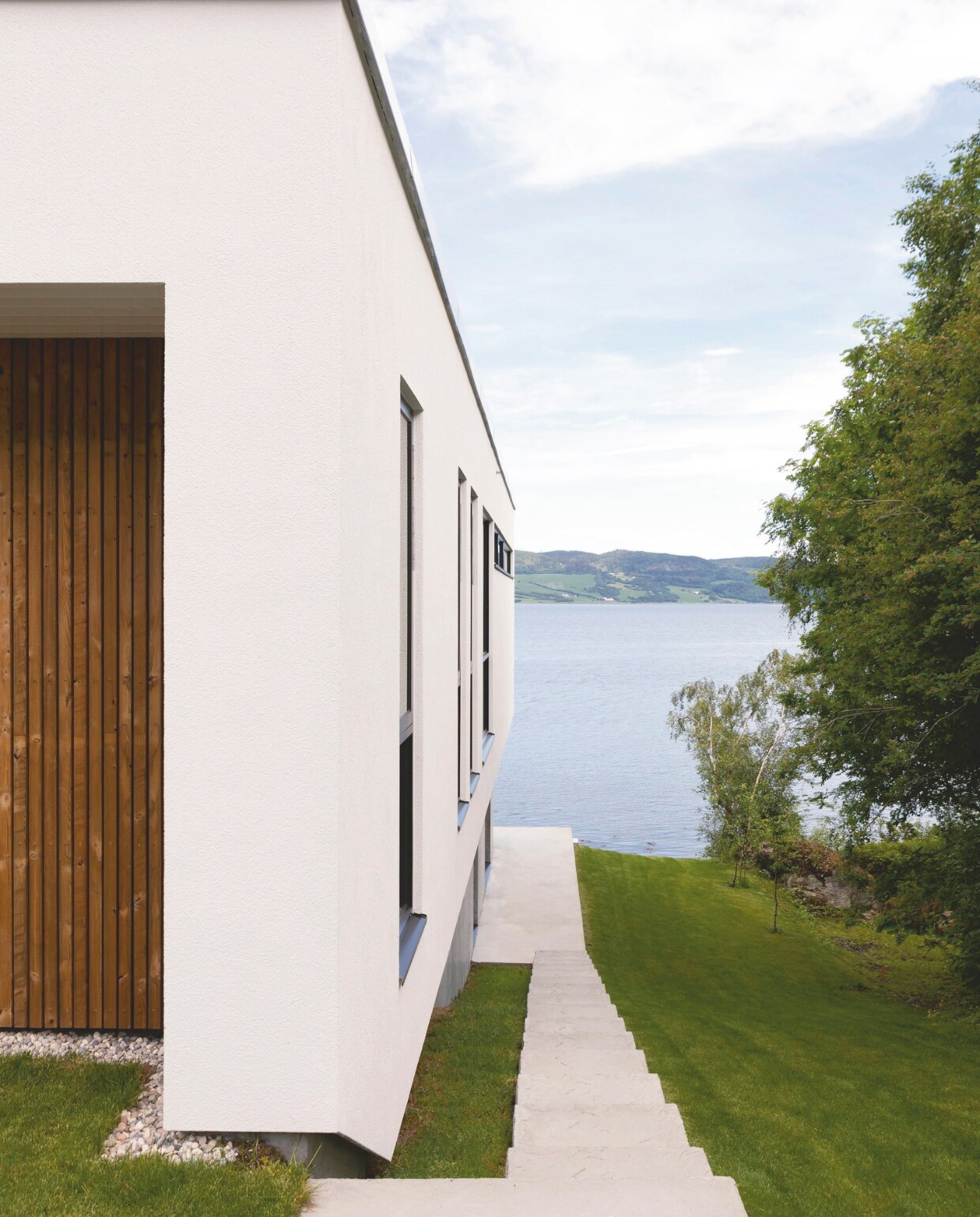 Een buitentrap verbindt de entree van het huis met het terras beneden aan de fjord, dat uitnodigt om te zwemmen. Stijlvol Wonen 03-2025 | Fotografie Anne Bråtveit | Tekst Caroline Westdijk
