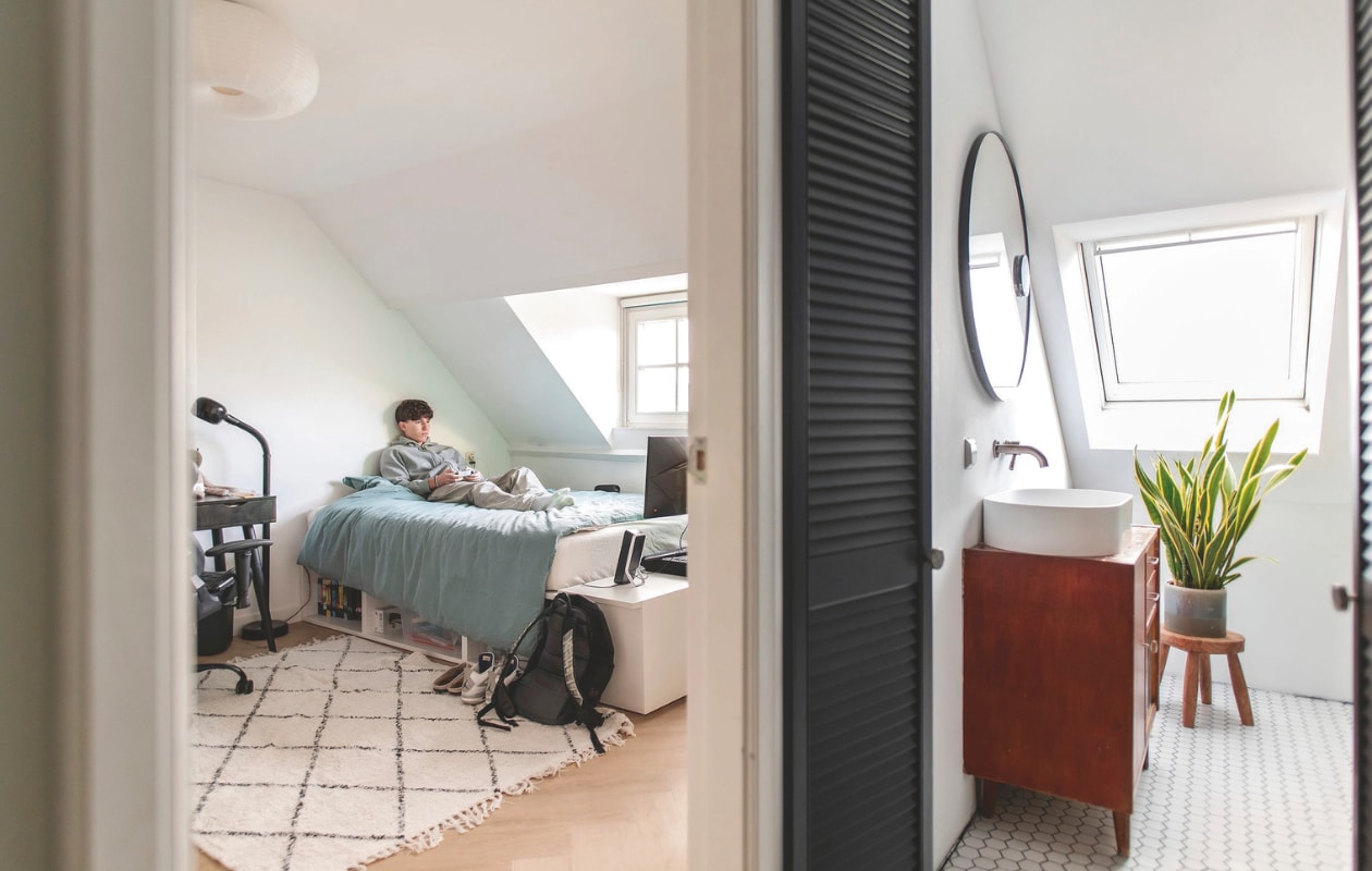 Kleed slaapkamer Søstrene Grene. Witte lage kast, plafondlamp Ikea. Bureau Kwantum. Bureaustoel Amazon. Zwarte lamp Fagerhult. Wastafelmeubel en kruk vintage. Wastafel Ideavit. Spiegel Ikea. vtwonen 03-2025 | fotografie Studio Keeelly | tekst Caroline Westdijk
