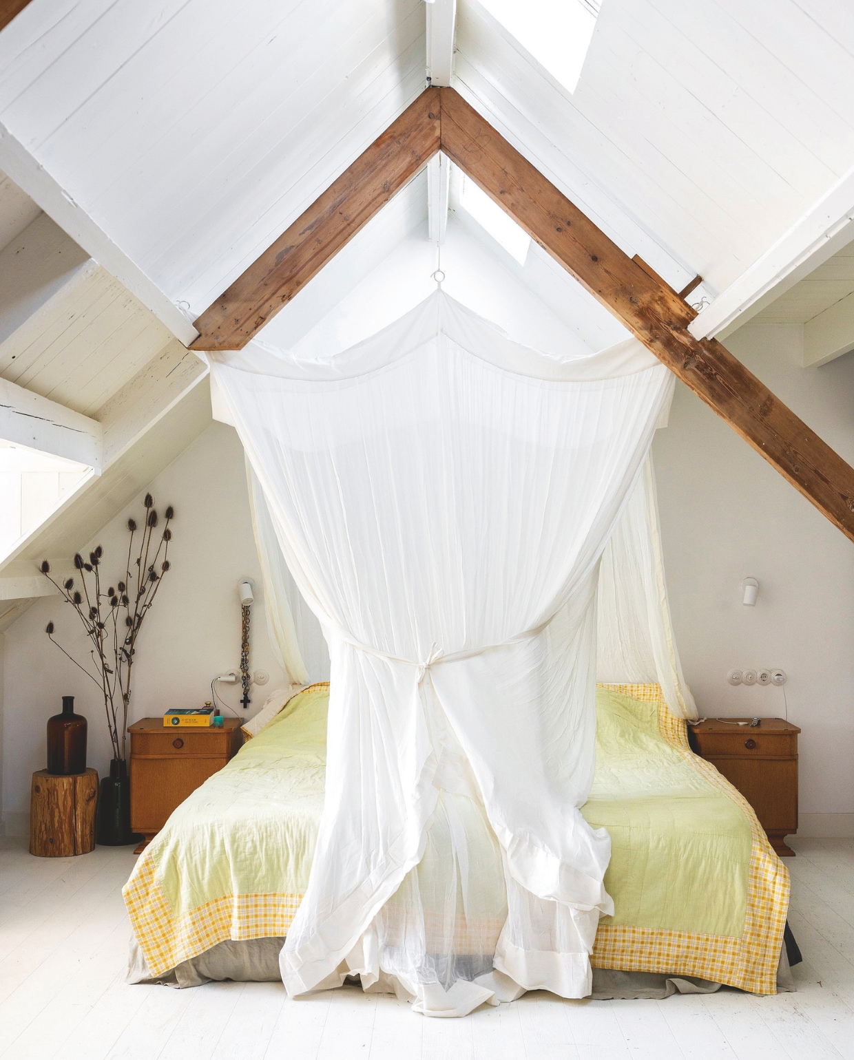 Vloerkleed Ikea. Nachtkastjes vintage uit Polen. Nachtlamp Hue van Philips. Bedhemel zelfgemaakt. Vaas erfstuk. Boomstam uit tuin familie. Muurverf Ral 9010. vtwonen 03-2025 | fotografie Margriet Hoekstra