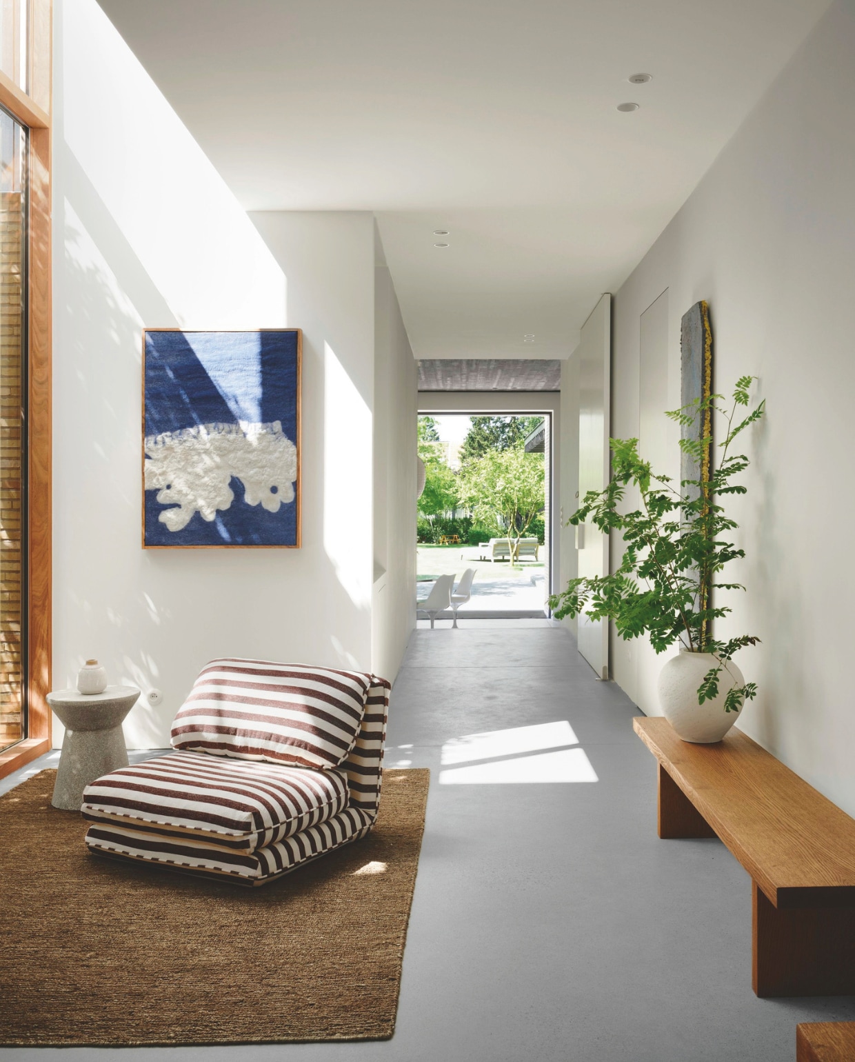 De grote houten raampartij geeft de hal extra warmte. Fauteuil Zara Home, tapijt Loook. stijlvol wonen | 2-2025 | fotografie Mr Frank | tekst Maya Toebat
