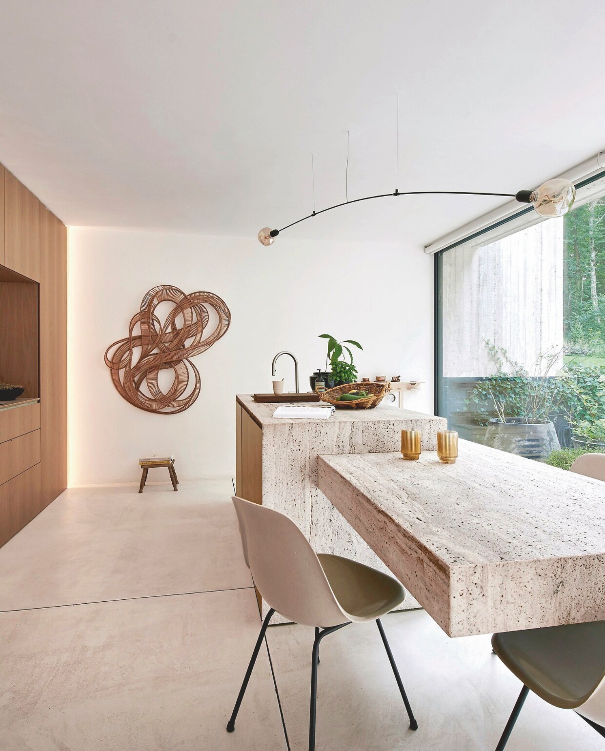 Keuken op maat gemaakt met travertijn en walnoothout. Vintage stoelen DSX van Charles en Ray Eames. Lithografie van Bernar Venet. vtwonen stijlvol 03-2025 | Fotografie Mr. Frank |Tekst Tanne Donjacour Gielen