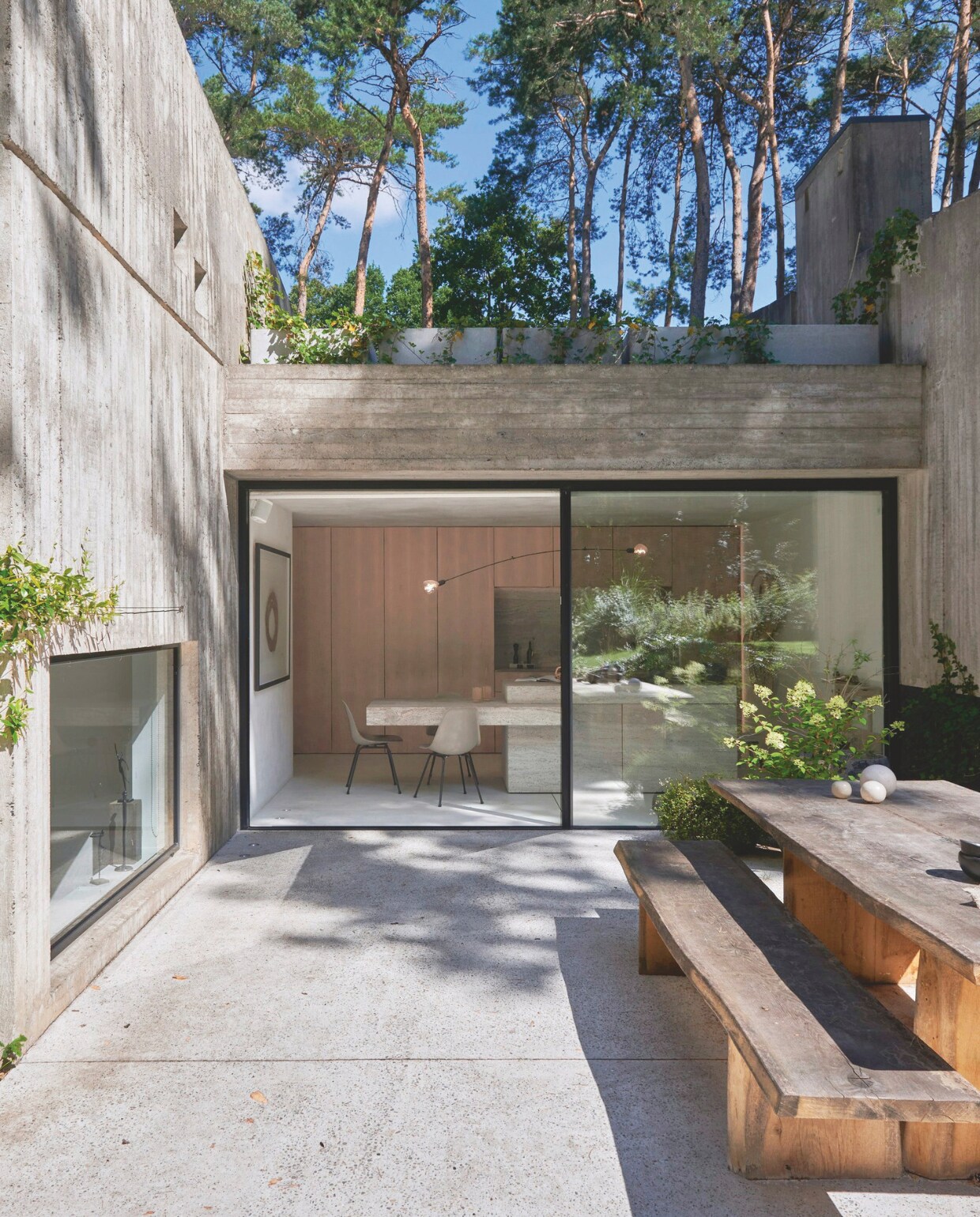 De architect van de villa, Marc Corbiau, heeft ook de tuin en het terras ontworpen. Zwarte Acapulco chairs. Houten tafel en banken op maat gemaakt. vtwonen stijlvol 03-2025 | Fotografie Mr. Frank |Tekst Tanne Donjacour Gielen