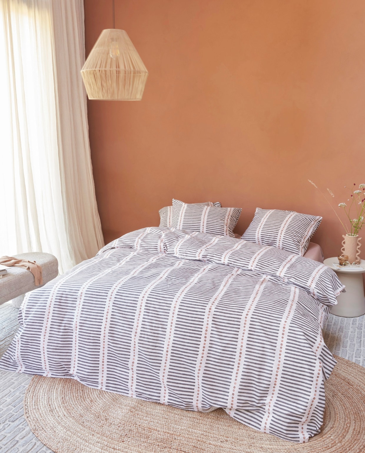 Katoenen dekbedovertrek Stip and Stripe in Blush vanaf € 49,95. M.m.v. hkliving.com (nachtkastje), by-boo.com (vloerkleed, hanglamp en stoffen bank), kwantum.nl (vaas). Overig privébezit. vtwonen 04-2025 | styling Kim Timmerman, Danielle Verheul | fotografie Richard Smit