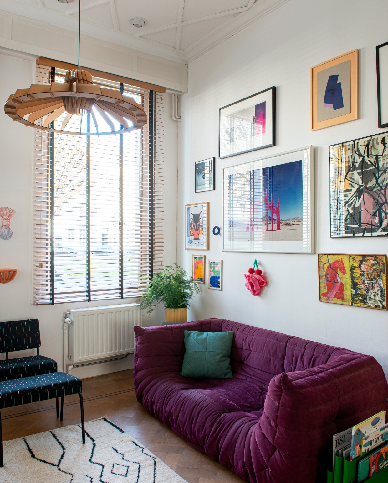 Vloerkleed Kenza&amp;Co, bank Togo van Ligne Roset, roze wandobject The Plastic Mine van Studio Thier&amp;vanDaalen, links daarvan twee werken van Stefhany Y. Lozano, daarboven zeefdruk Maaike Canne, in het midden foto Jean Ruiter, daarboven foto François Berthier, ernaast collage Studio Rens, midden rechts zeefdruk Palefroi, rechts onder schilderij Nina Versporten, houten lamellen onbekend. vtwonen 02-2023 | styling: Jeske Weel | fotografie: Caroline Coehorst