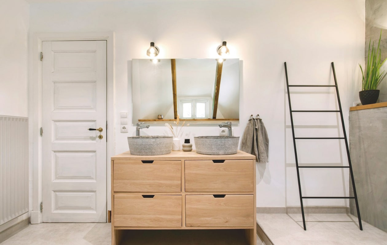 Vloer van beton. Vergelijkbaar houten wastafelmeubel Van Heck Badkamers. Soortgelijke kapstok-ladder Estivar van La Redoute. vtwonen Landelijk 03-2025 | Styling Miriam Hannemann | Fotografie André Reuter | Tekst Joëlle Baelde