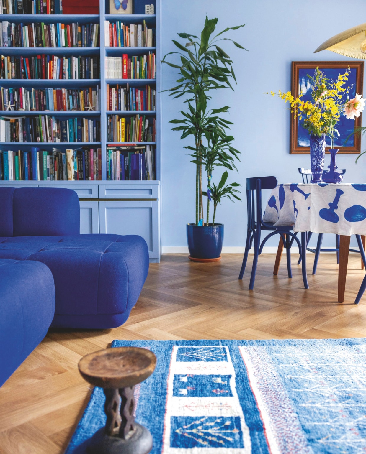 Muurkleur NCS S 1030-R80B. Vloer pvc van Laminaat2Go. Maatwerk boekenkast Beitel Beestje, in NCS S 1030-R80B. Tapijt Gabbeh via Nain Trading. Bijzettafel gekregen. Eettafel Gubi. Stoelen Oud is Nieuw in RAL 5002. Bank Quilton van Hay. Tafelkleed en schilderij zelfgemaakt vtwonen 04-2025 | fotografie dana van leeuwen | tekst merel van der lande