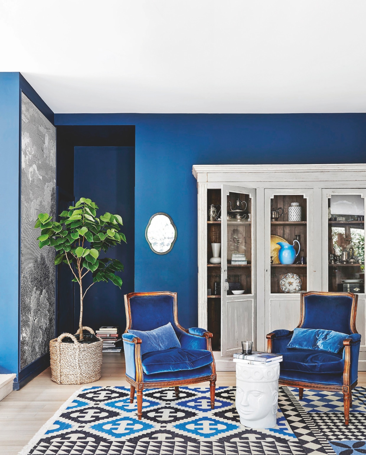 Muurkleur afgestemd op Hague Blue van Farrow & Ball. Behang Arcadiavan Anthropologie. Kast The Bronte Tram. Vintage fauteuils bekleed met katoenfluweel van Maharam. Vloerkleed Kilim Palermo van Gan via Hub furniture. Spiegel Leonard Joel. Bijzettafel The king of Cambodia van Nyary Es. vtwonen 04-2025 | styling Fiona Richardson | fotografie Lisa Cohen | tekst Mirjam Rosema-Verhulst