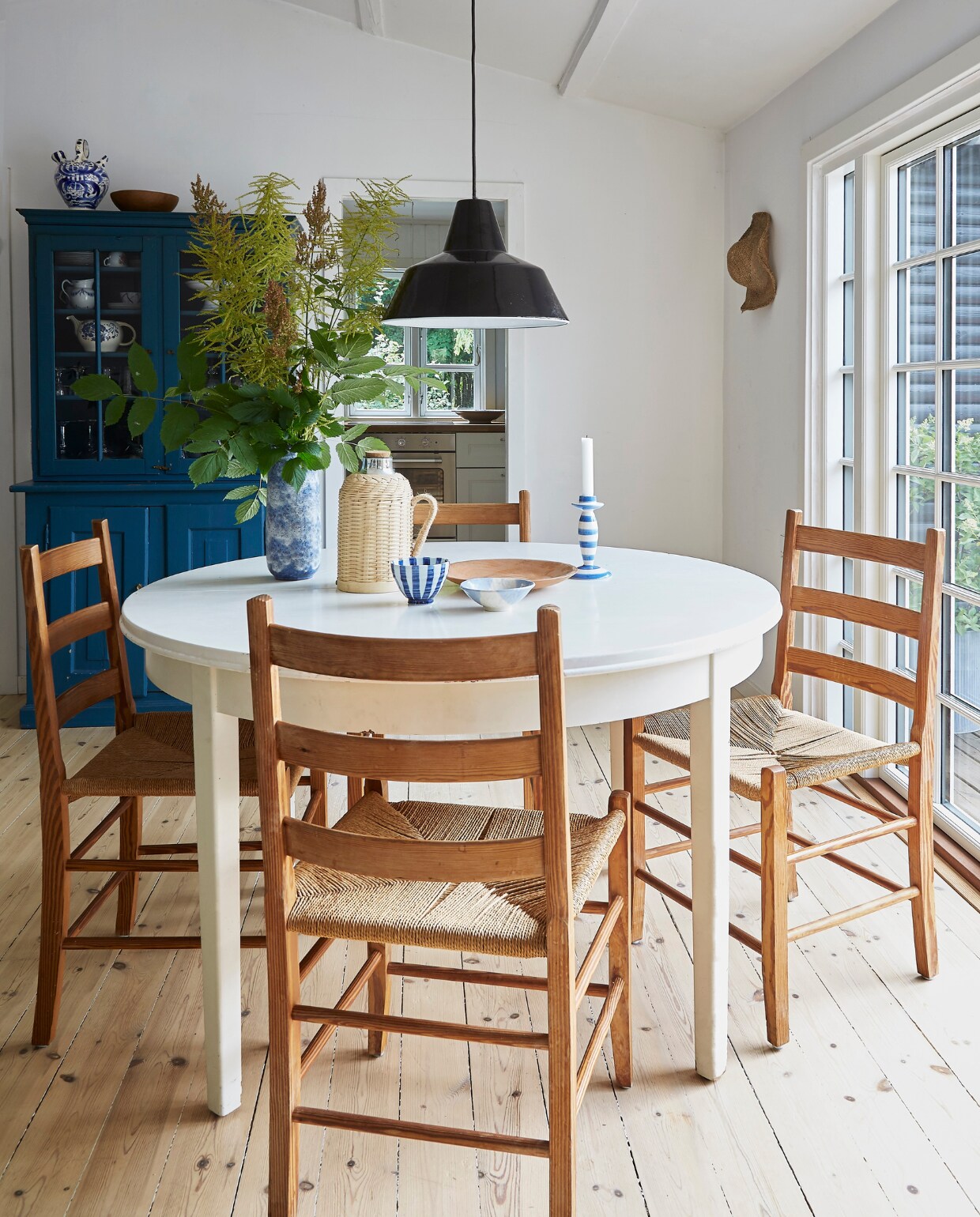 Eettafel en stoelen dba.dk, de Deense versie van Marktplaats. Kan Søstrene Grene. Kom en vaas  Saikindo Ceramics. De lamp is een familiestuk. Kast gekregen van een buurvrouw.  De originele houten vloer is geschaafd en met loog behandeld. vtwonen Landelijk 4-2025 | Styling Rikke Graff Juel | Fotografie Anitta Behrendt | Tekst Wilma Tjalsma-Smits