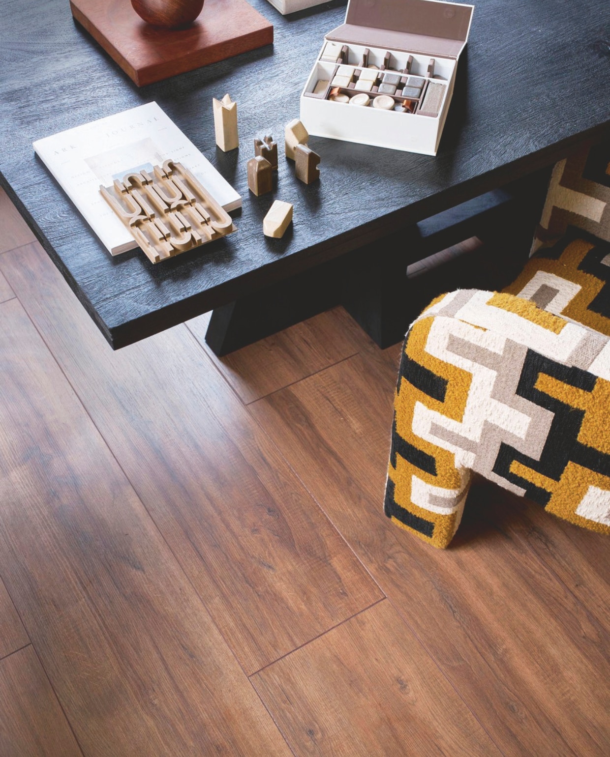 Laminaat XL in Collar Warmbruin, lamel 138x32,6x0,8 cm, met groef, per m² € 32,99.M.m.v. deeekhoorn.nl (eettafel Woood), rapture.amsterdam (fauteuil), zarahome.com (schaakstukken). Overig privébezit. vtwonen 05-2025 | styling cleo scheulderman | fotografie jeroen van der spek