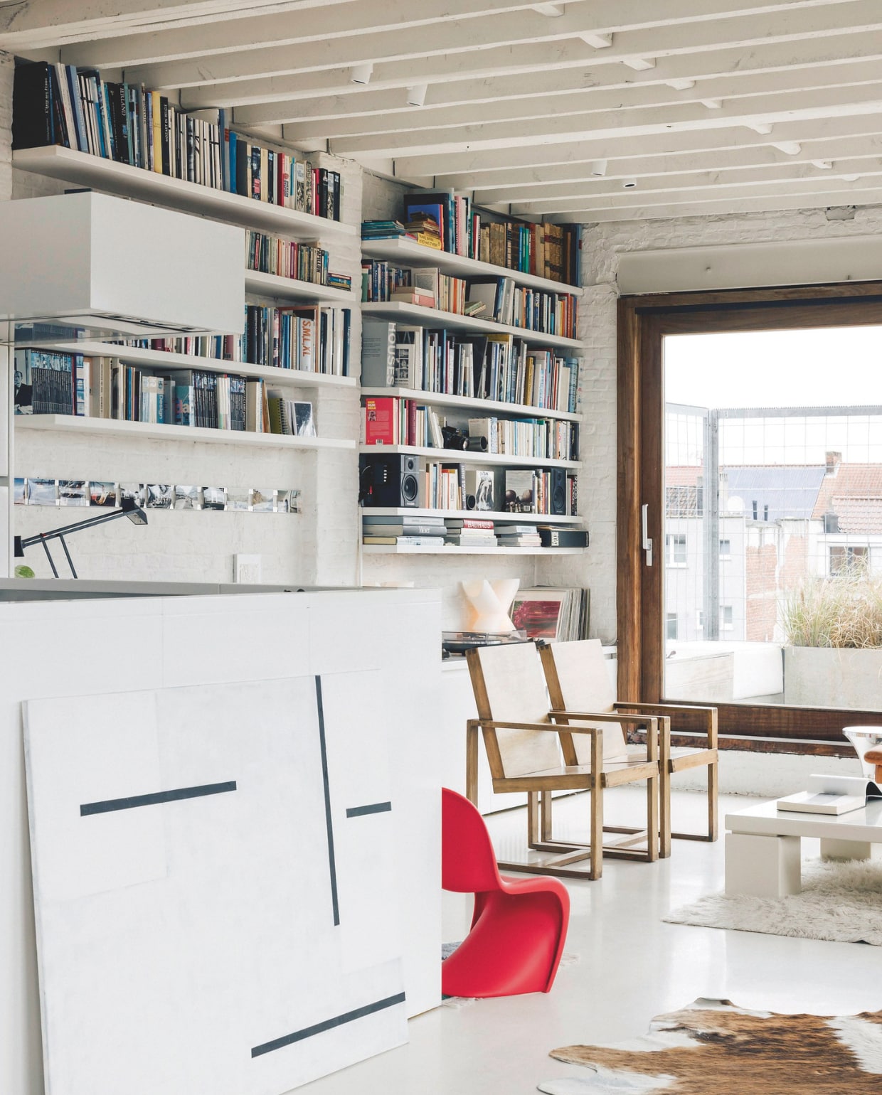 Kunst is een grote passie van Frédérique. Overal staan of hangen schilderijen, zoals dit abstracte werk van Michèle Goossens, een van de kunstenaars gepresenteerd door LOFT22 art space. De houten stoelen zijn vintage, waarschijnlijk door Pierre Chapo. Stijlvol Wonen 05-2025 | fotografie Katoo Peeters